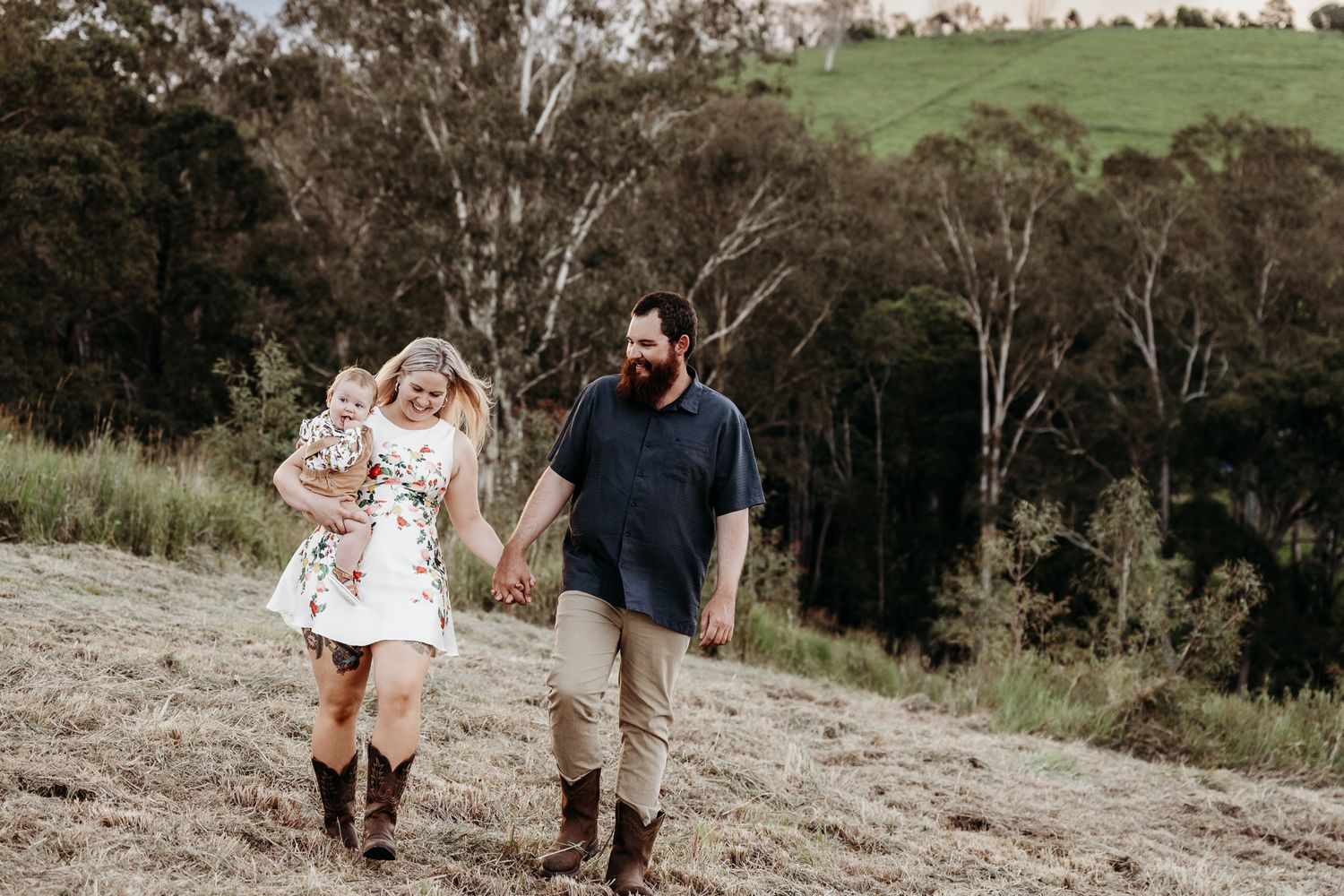 Couple walking together on a hillside path surrounded by trees.