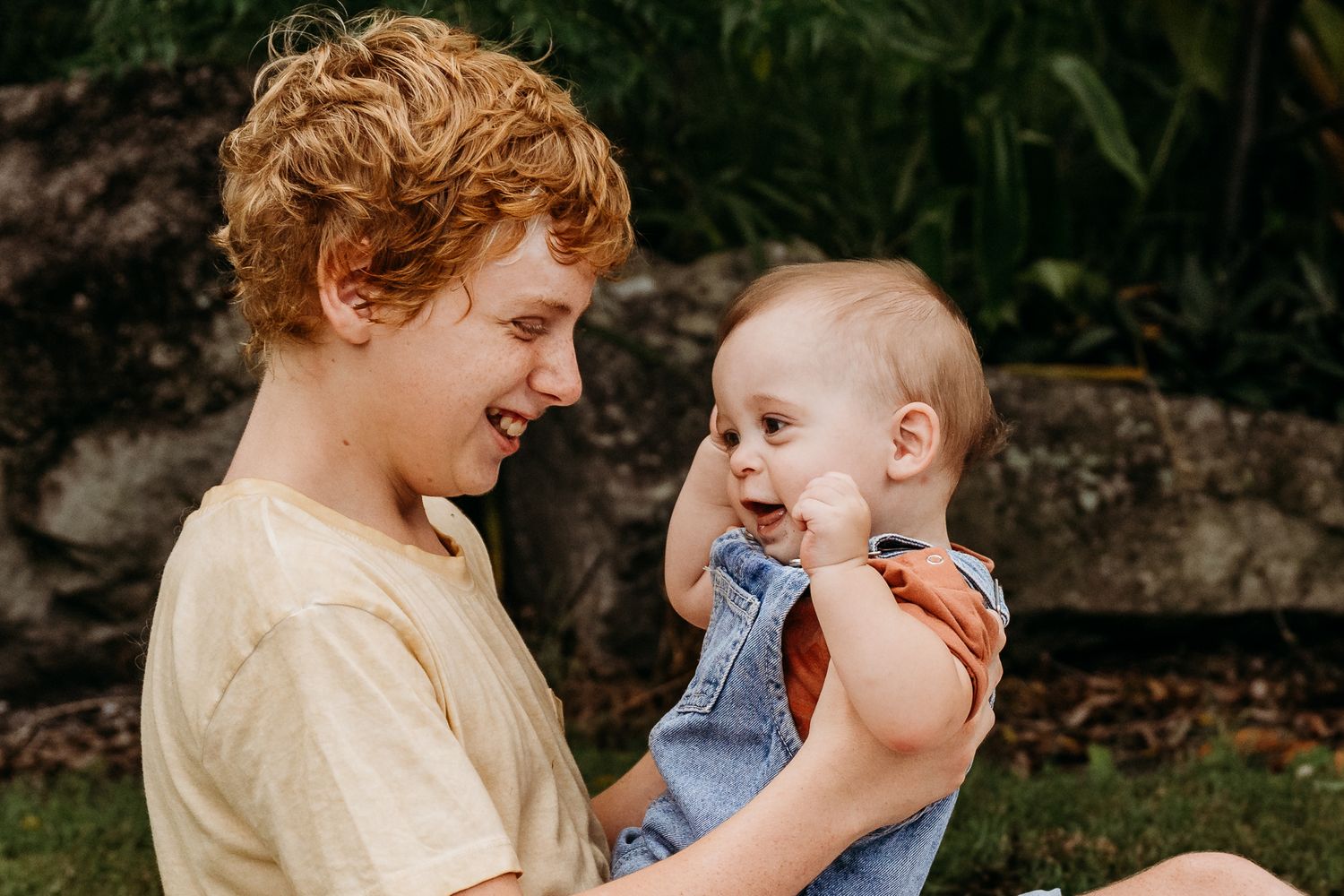 A tender moment of connection between caregiver and baby in denim overalls.