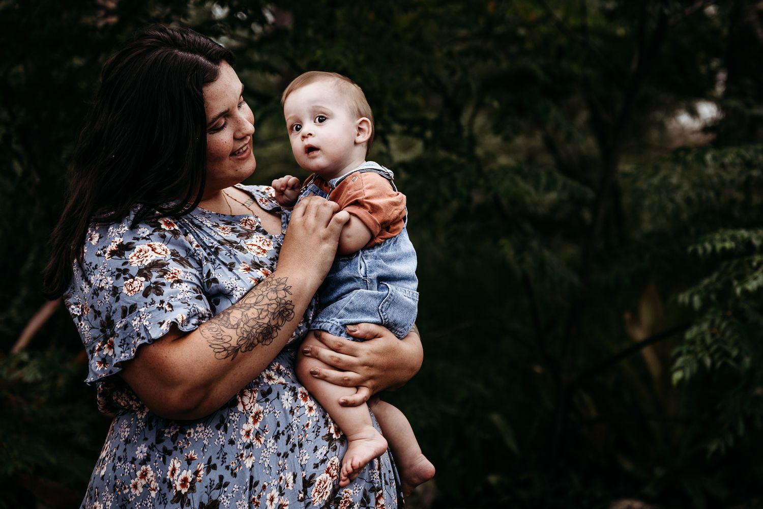 Tender moment between parent and baby in casual outdoor setting.