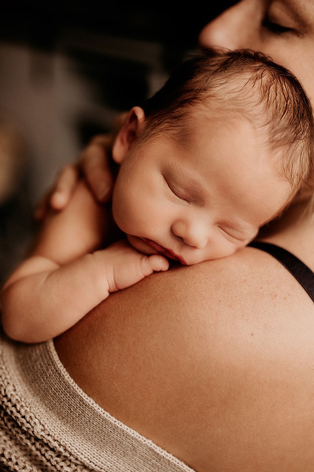 A newborn baby girl sleeps while laying over her mother's shoulder. Hawaii Newborn Photographer.