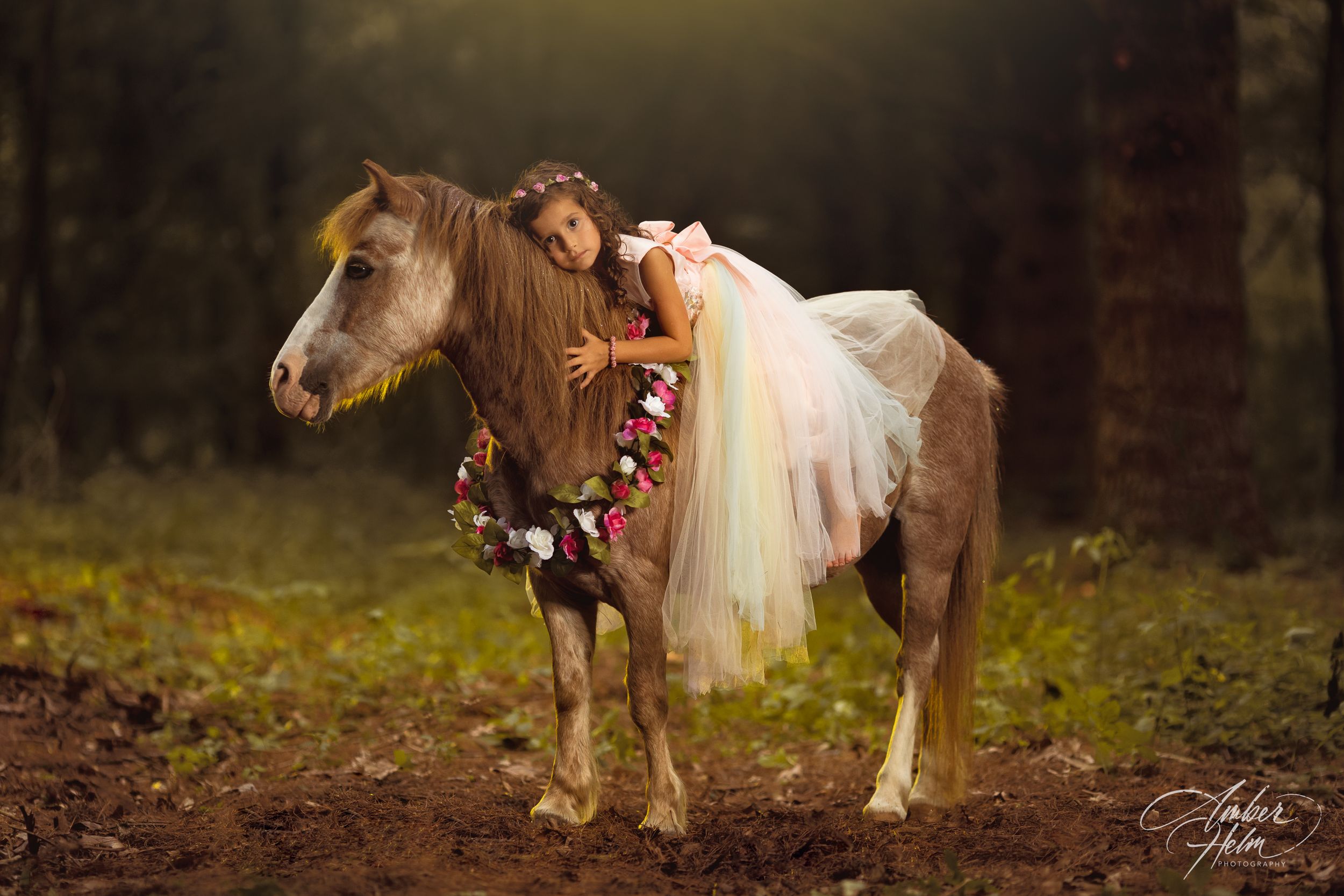 A cowgirl princess and her pony stand in a wooded clearing, looking like a princess from a fairytale.