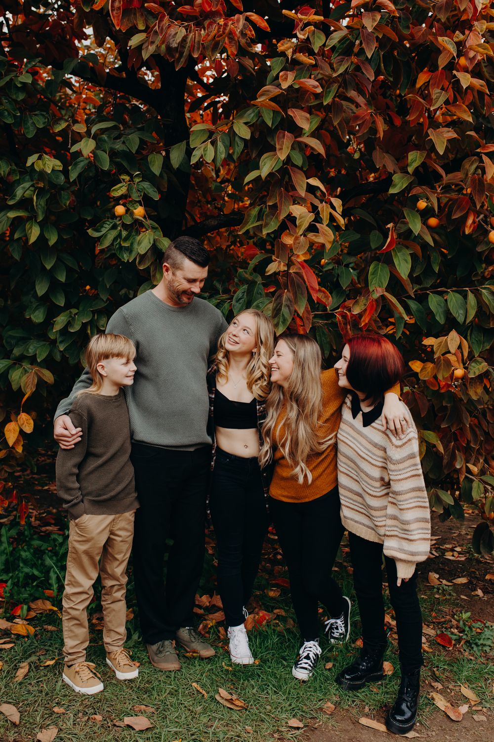 Small group poses together against autumn foliage backdrop.