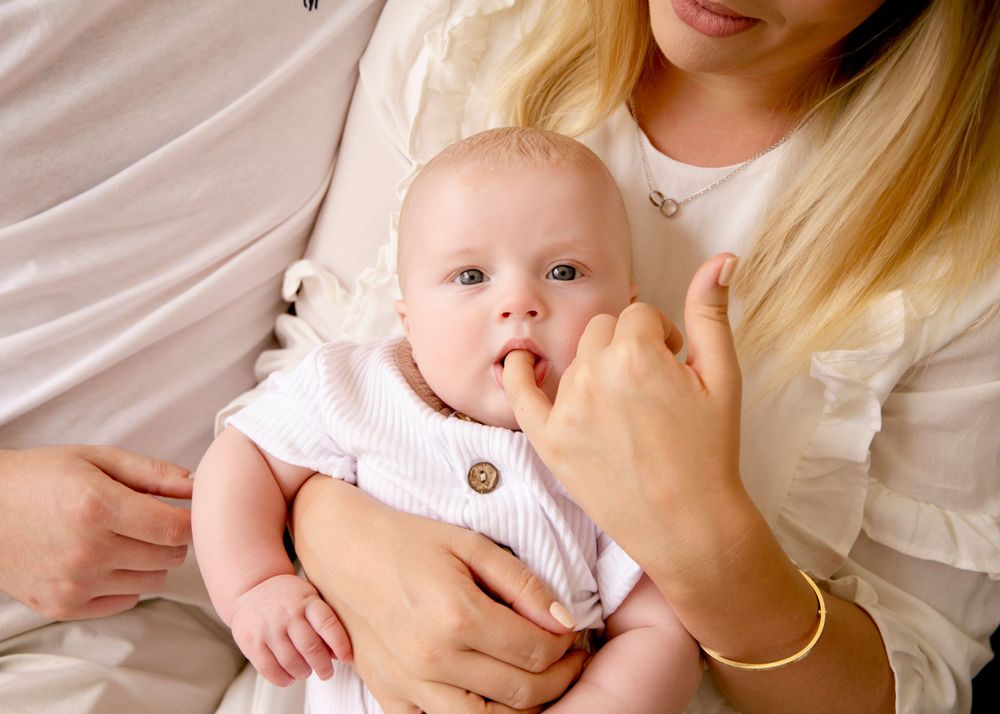 Sweet baby sitting on his Moms lap sucking her finger.  The photo was taken by Alpharetta based Newborn Photographer