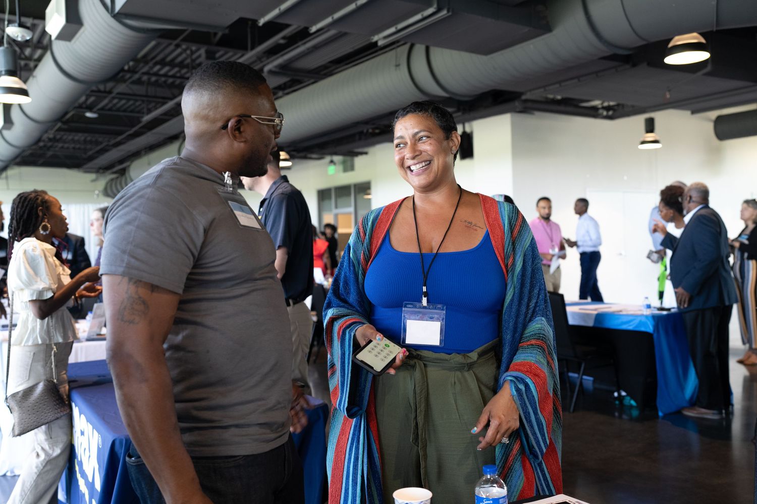 Smiling man and woman network at community event, engaging in friendly conversation with others networking in the background