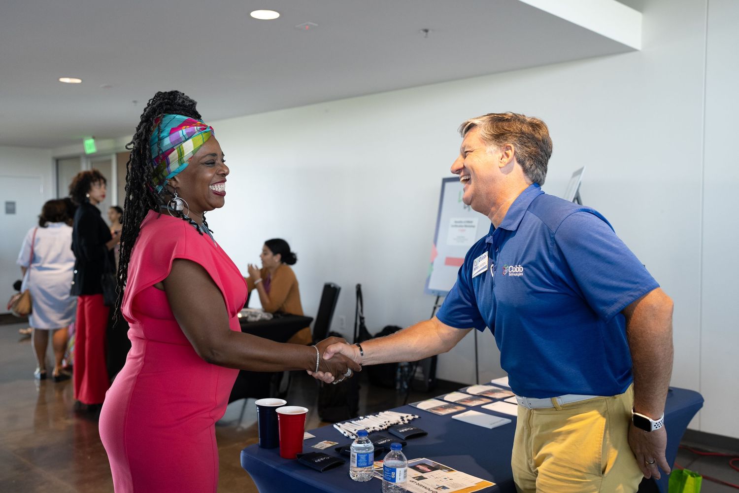 Man and woman shake hands at networking event booth, building professional connections in a welcoming business environment