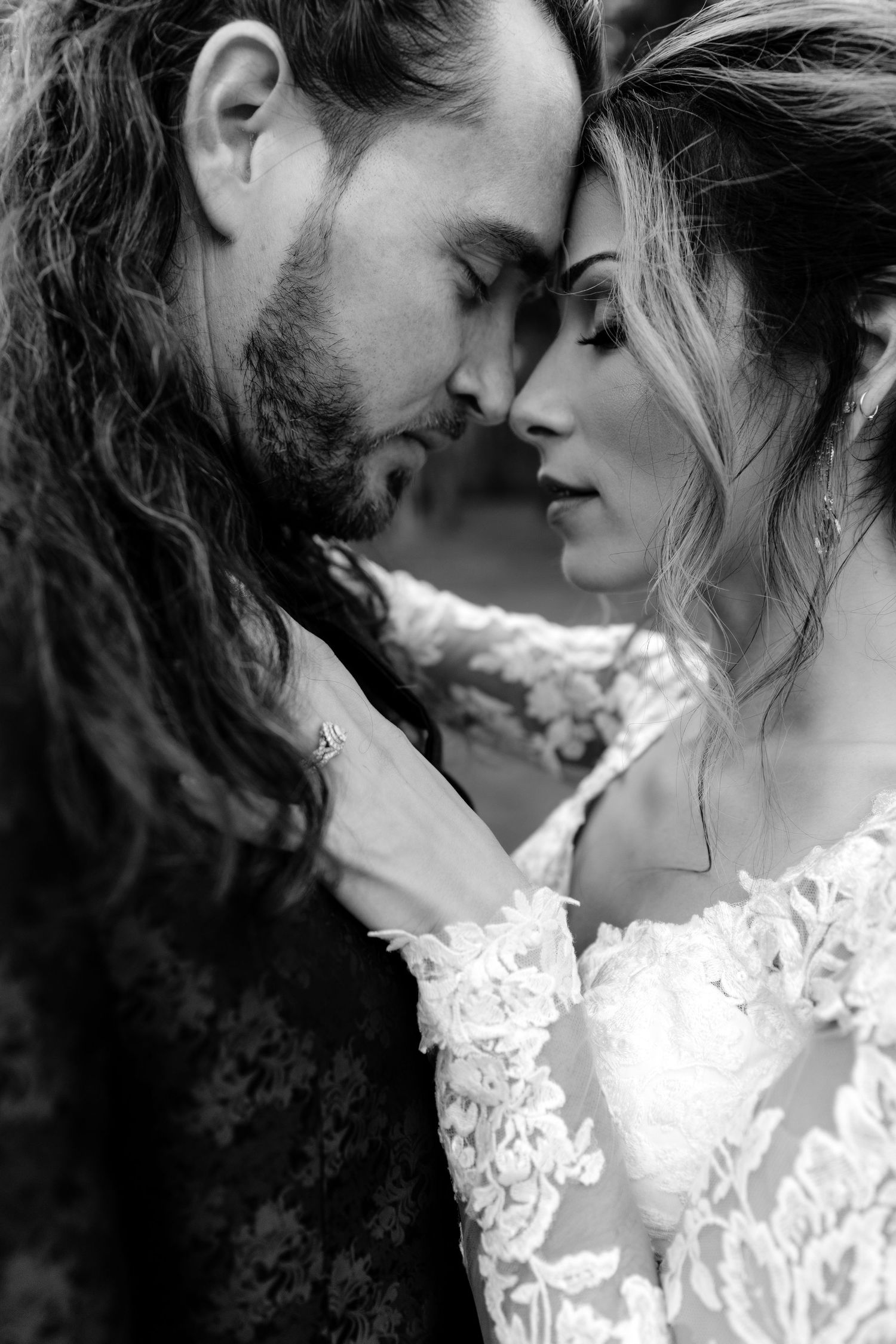 Intimate black and white portrait of a couple in wedding attire sharing a tender moment.