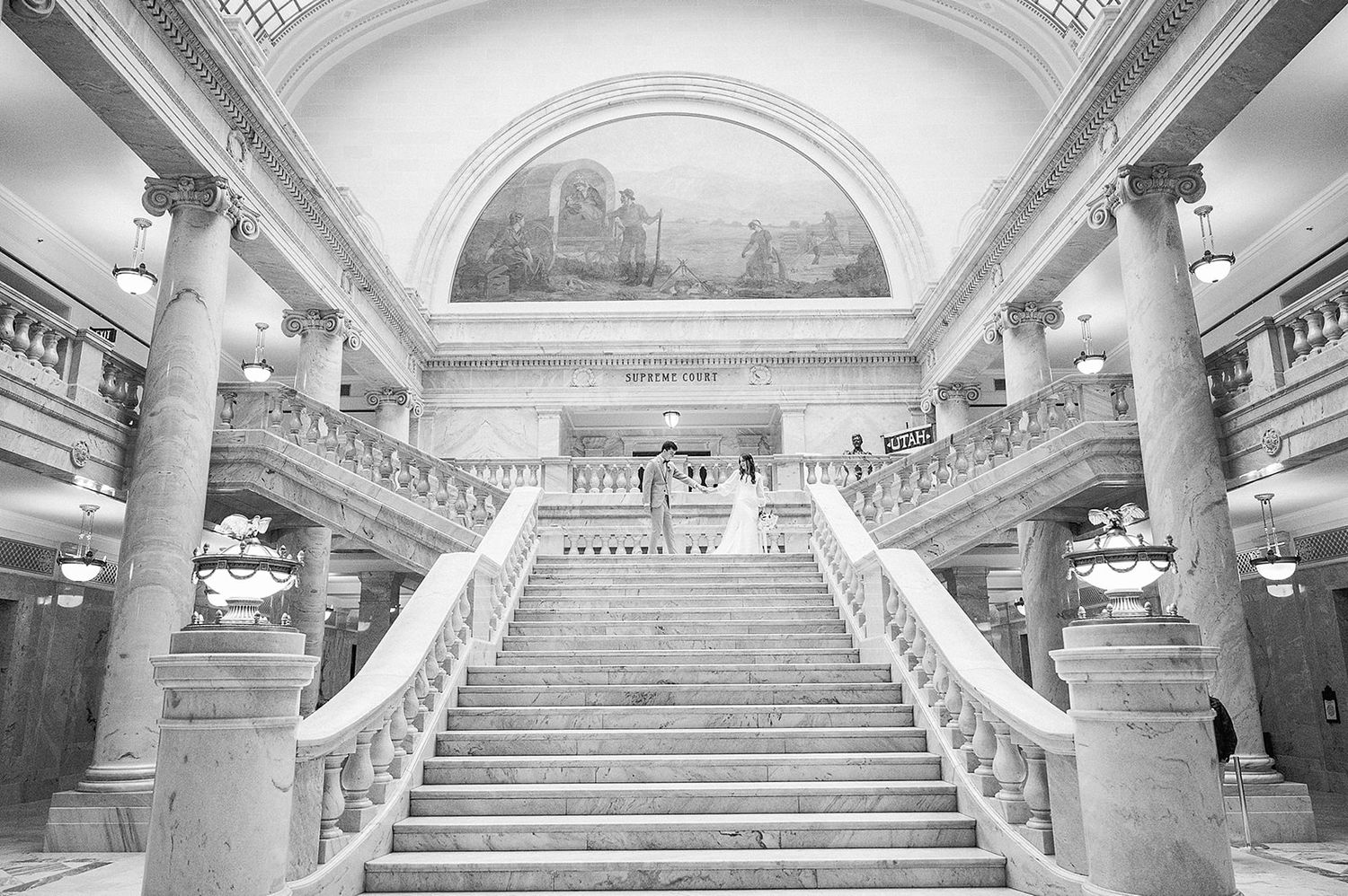 Historic marble staircase with classical columns and arched ceiling in black and white photography.
