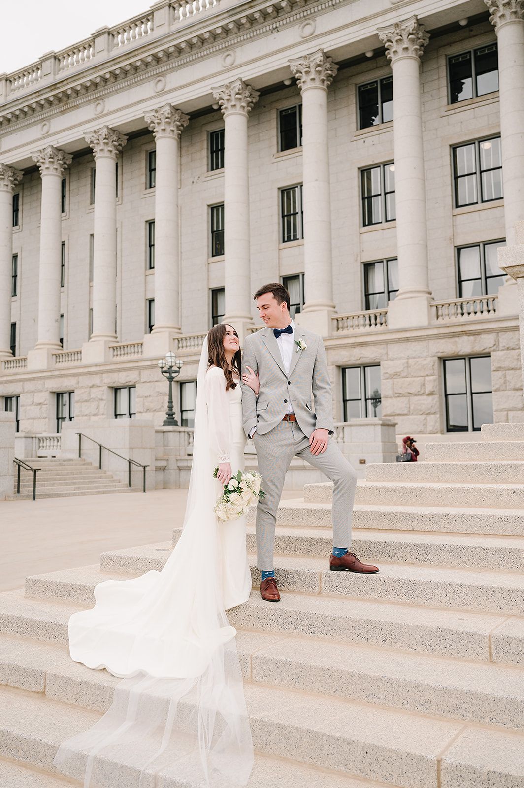 Wedding photo on courthouse steps with elegant white dress and light gray suit.