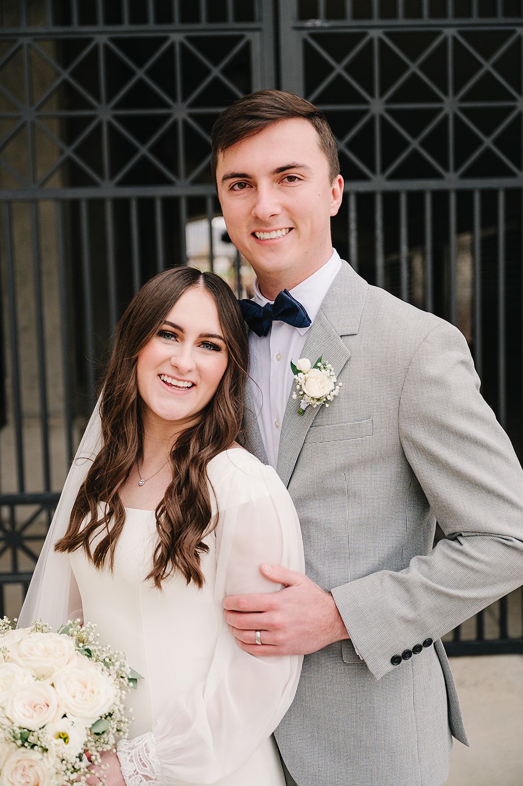 Wedding portrait in front of ornate iron gates.