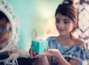 Tiffany blue gift box being presented against turquoise wall with ornate mirror reflection.