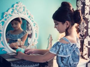 Elegant vanity scene with vintage mirror showing reflection against turquoise wall with lace details.
