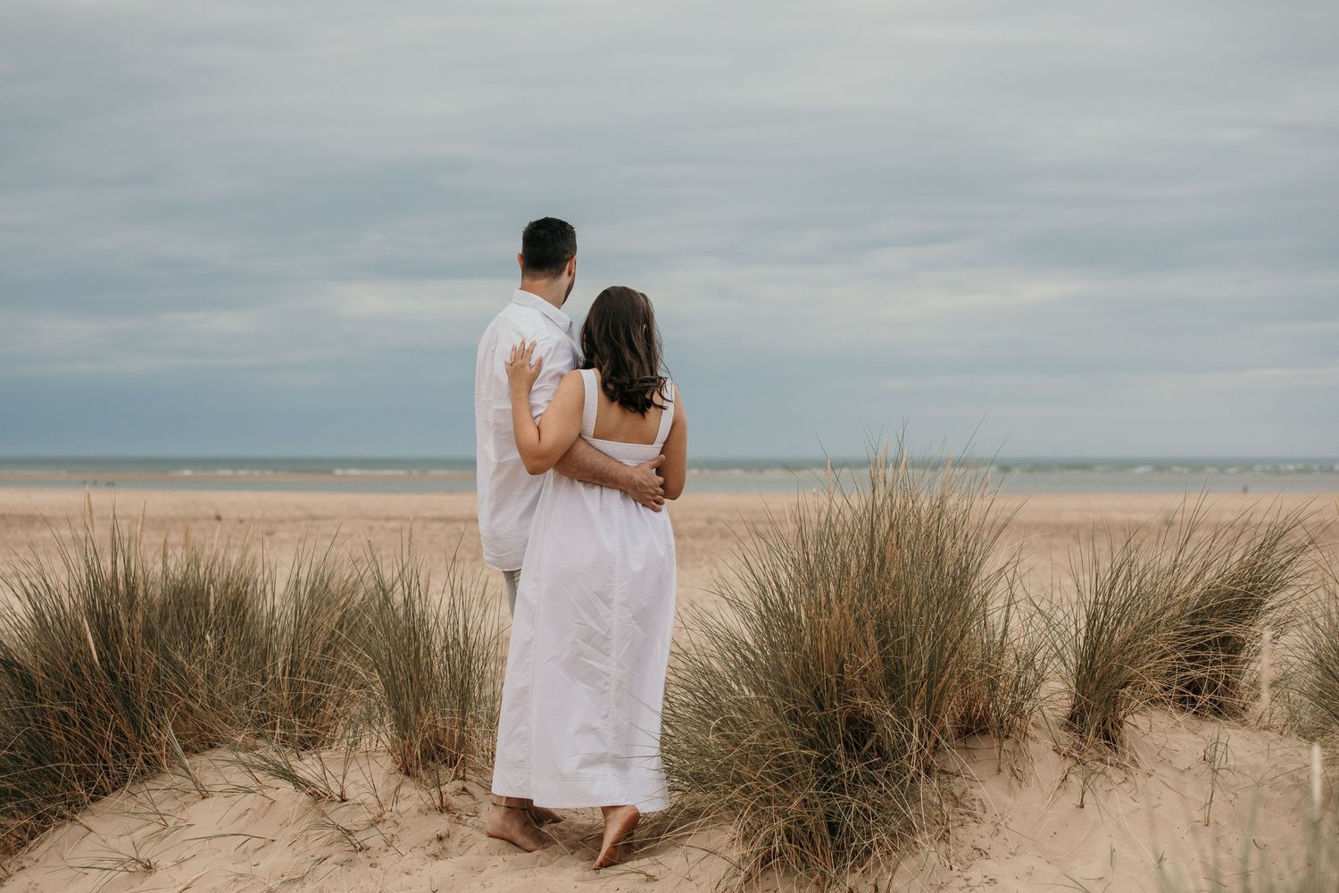 couple arms around each other in the sand dunes at Norfolk beach