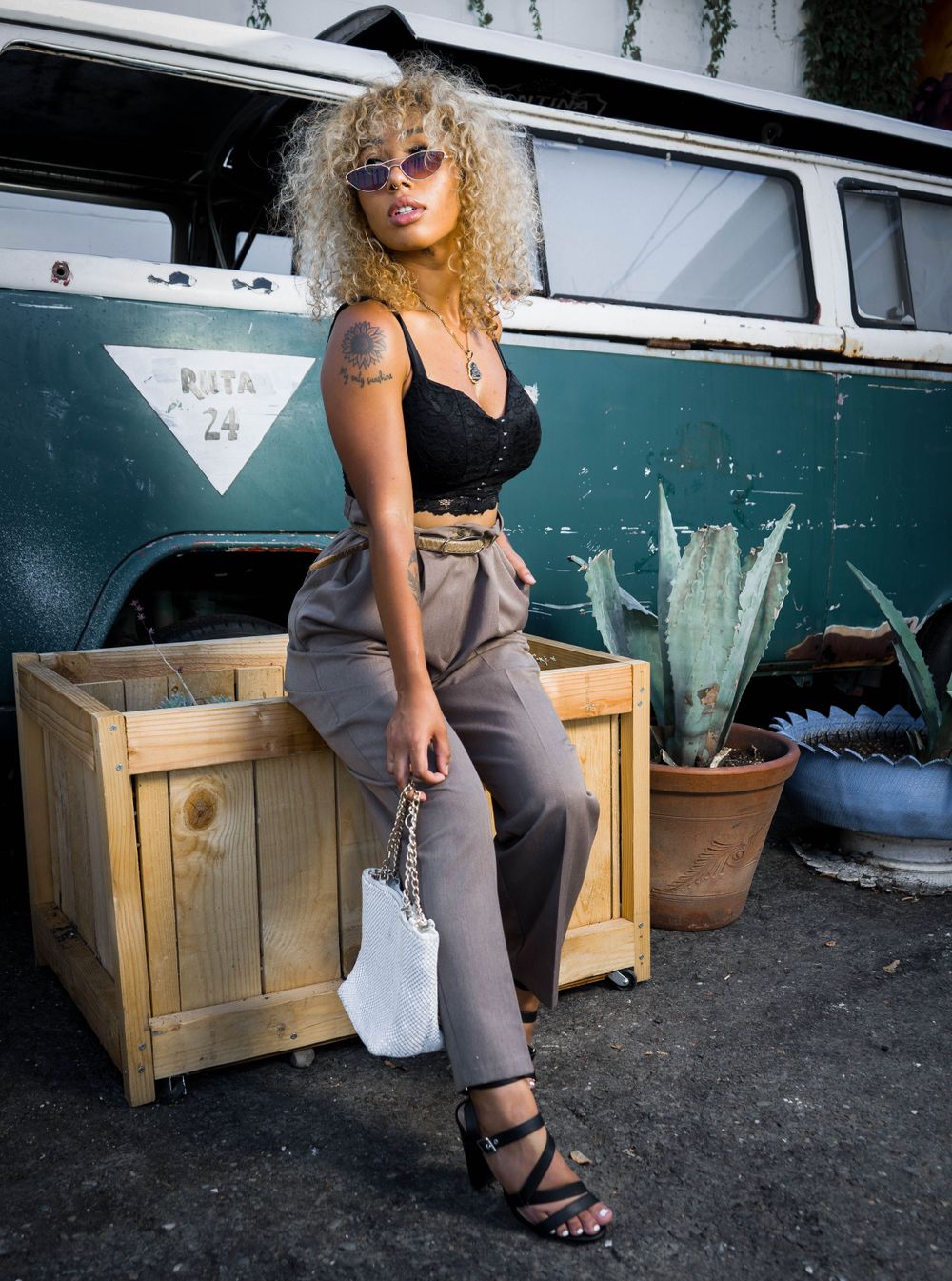 Beautiful curly hair woman in heels, black top and classic van background in editorial photoshoot