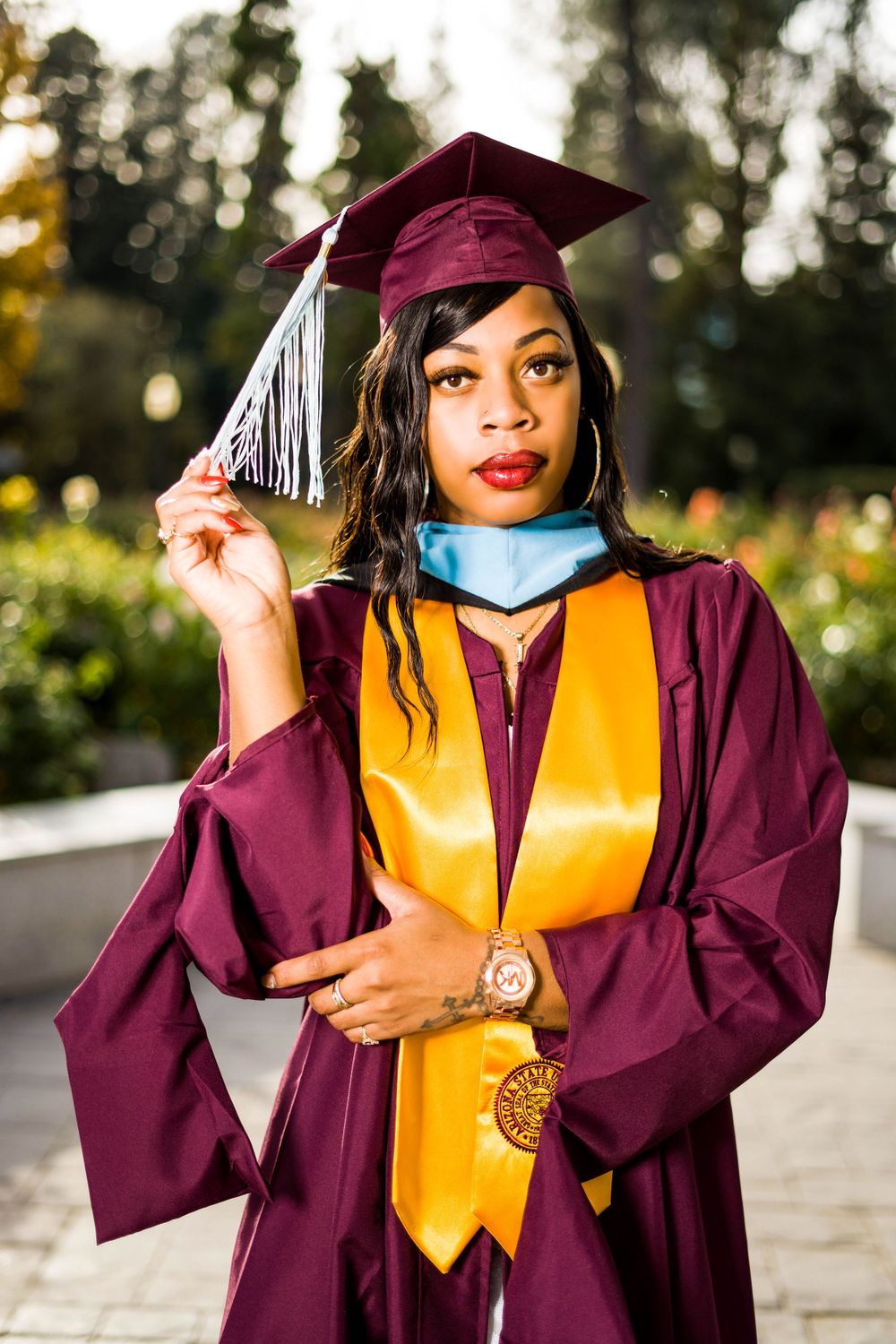 Graduation picture holding the tassel in a rose garden photoshoot