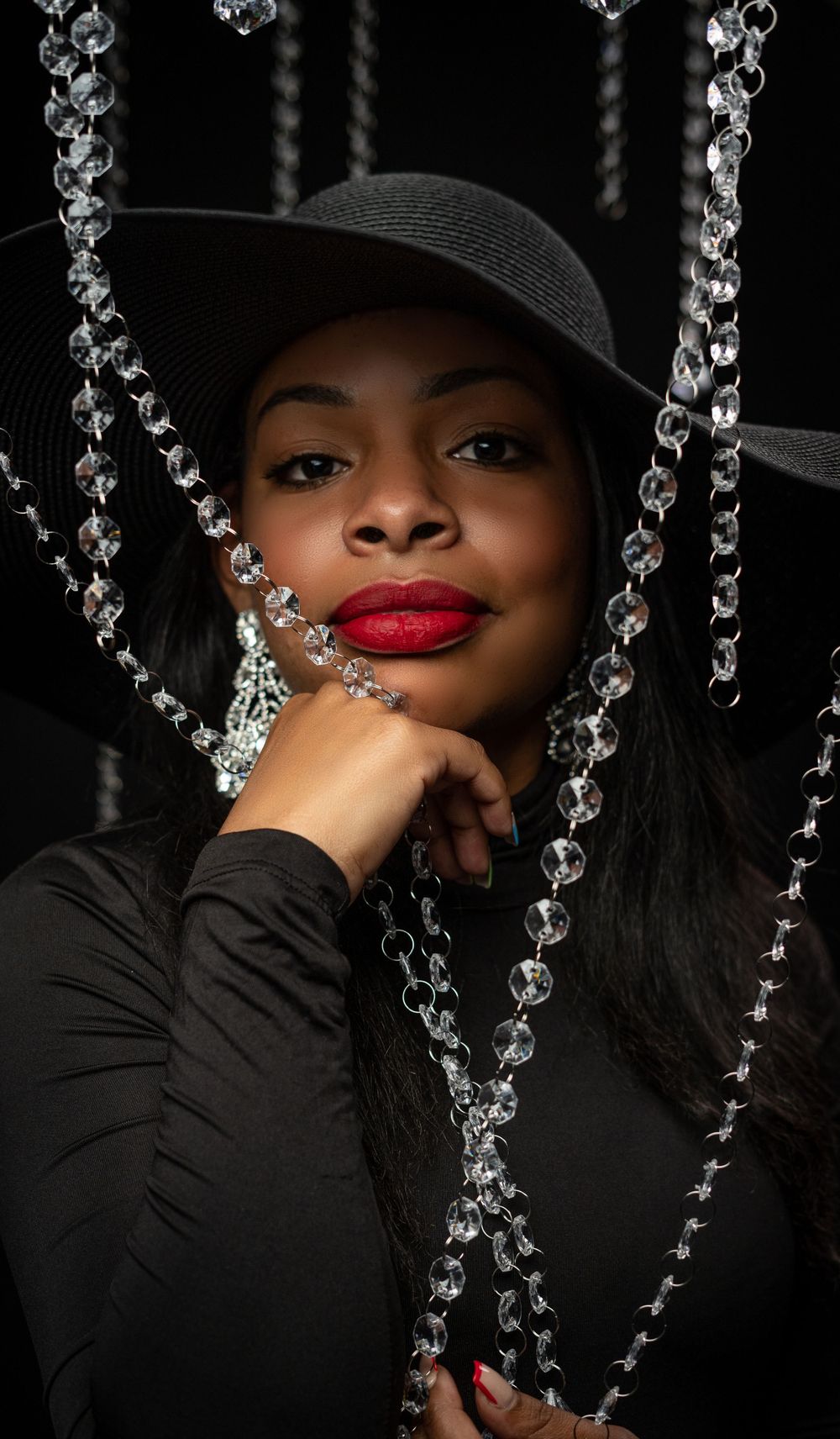 Black woman with red lipstick in one piece draped in diamonds for editorial photoshoot
