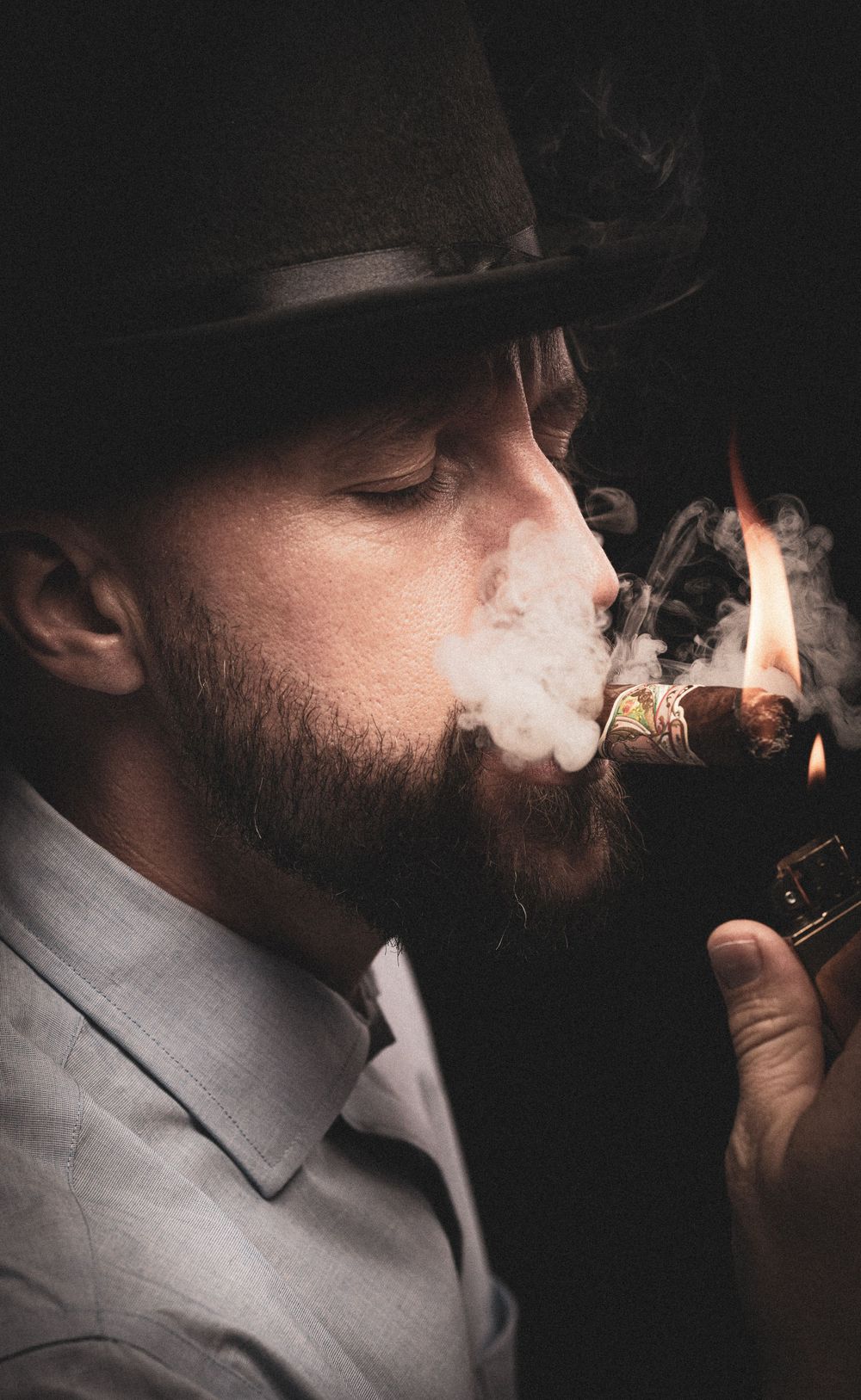 Black top hat and man lighting a cigar headshot