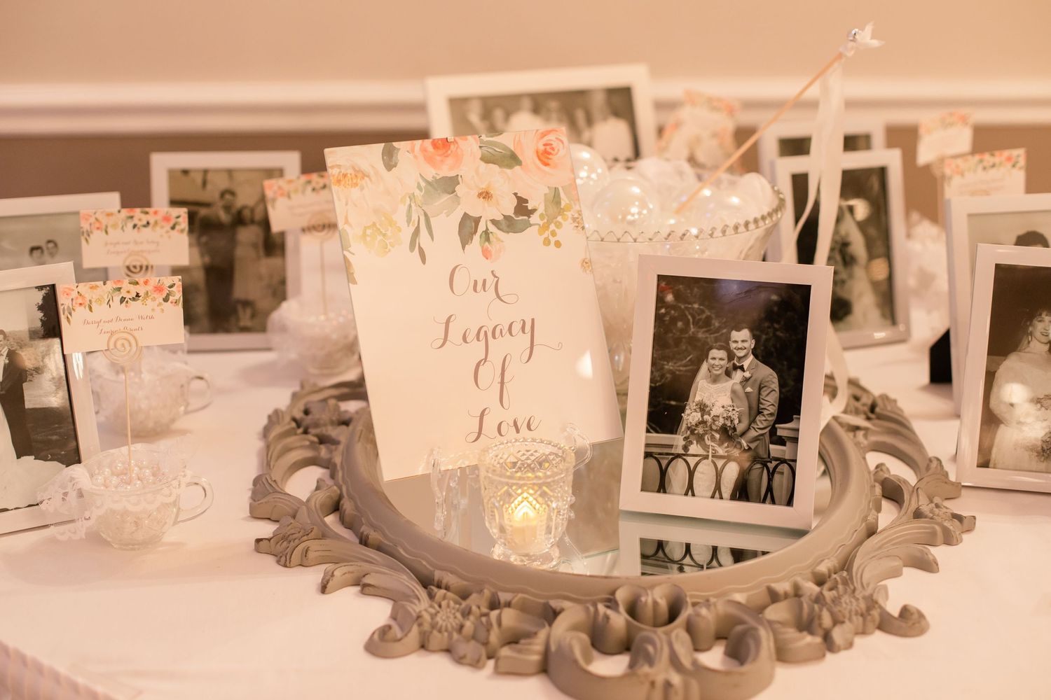Vintage-style wedding display with candlelight and photo frames on decorative silver tray.