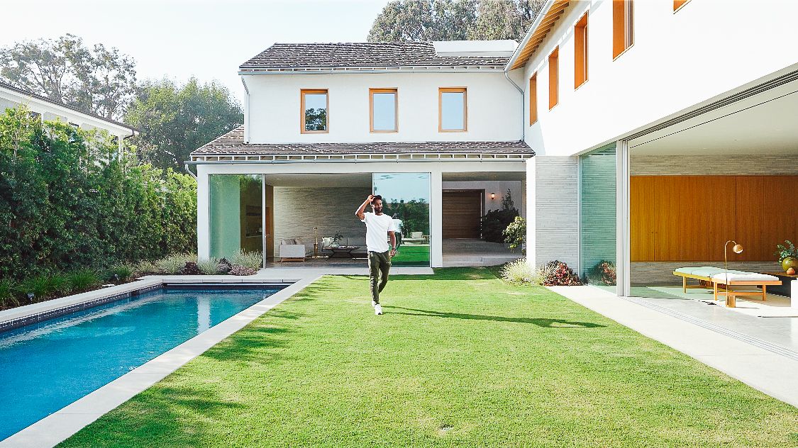 Modern house exterior with lap pool and manicured lawn in backyard.