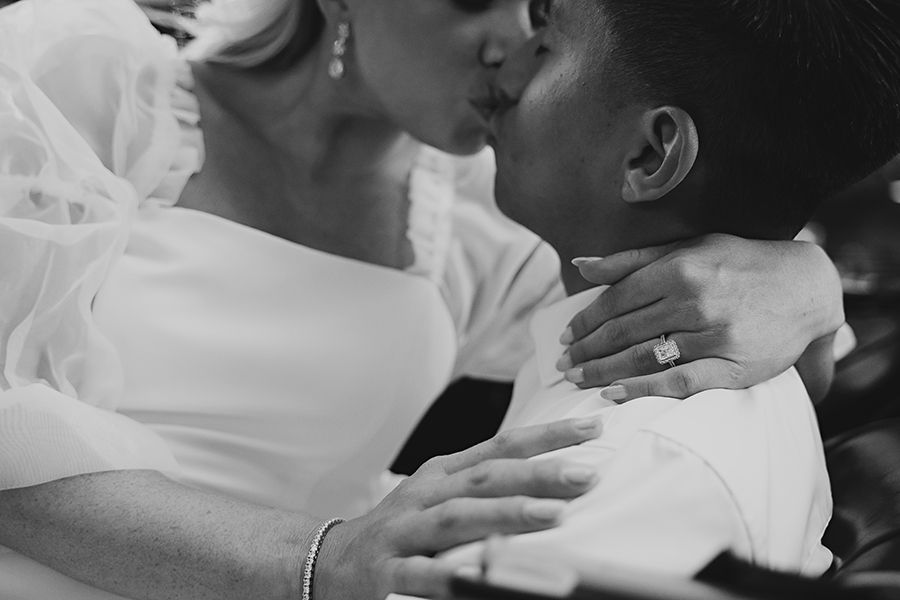 Close-up black and white image showing tender embrace with hands and white fabric.