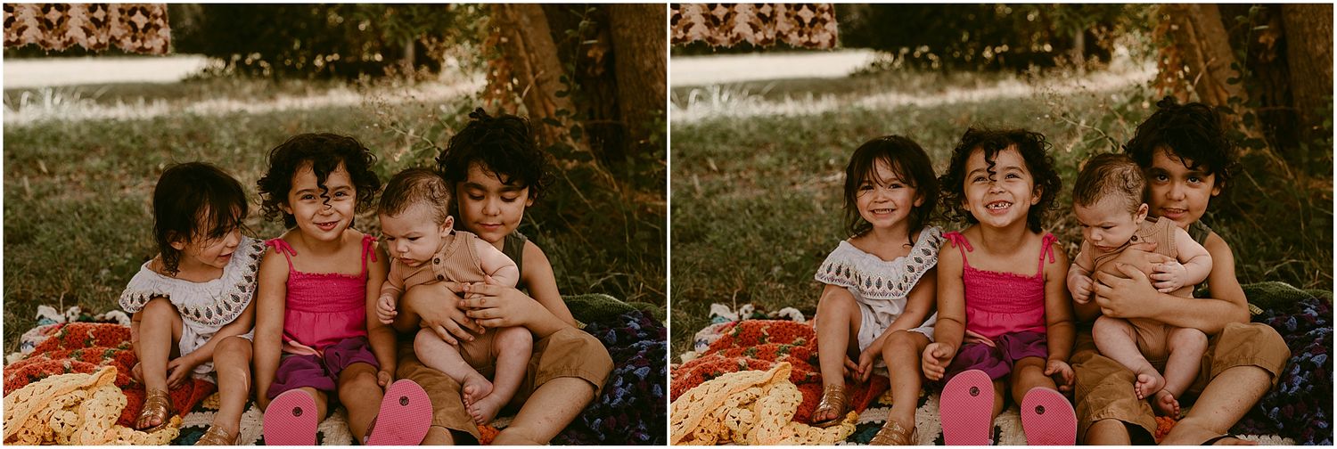 Children smiling and enjoying time together on a picnic blanket in the grass.