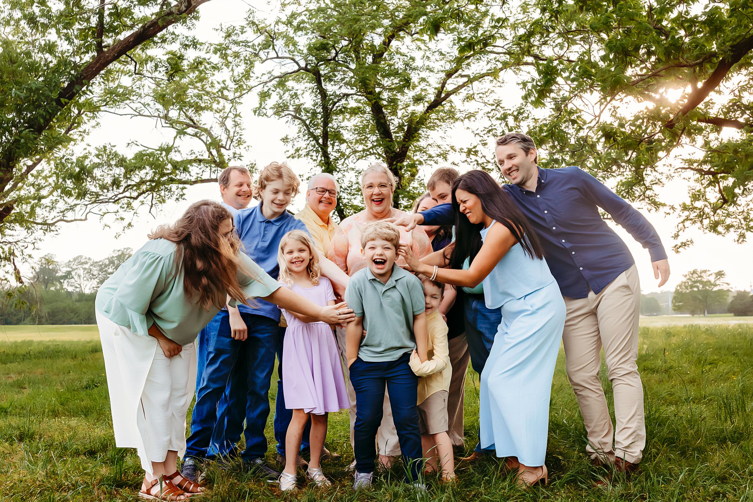 A joyful extended family gathering outdoors in a grassy field during golden hour.