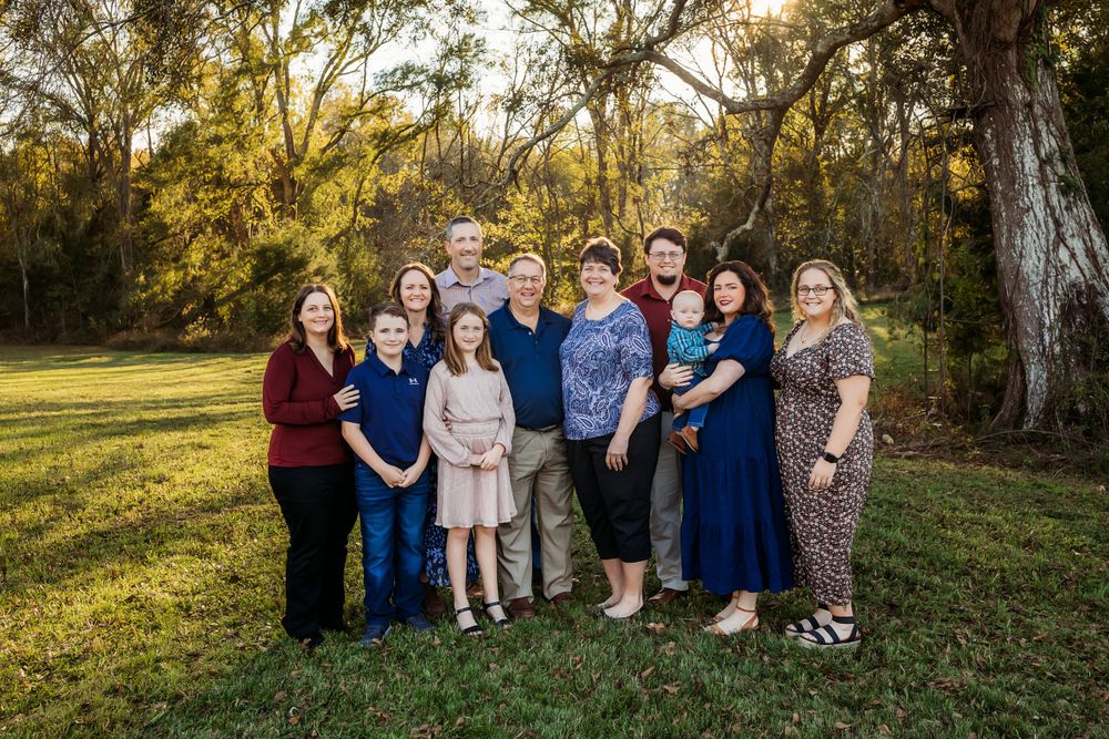 Large family group portrait taken outdoors under Spanish moss trees at sunset.