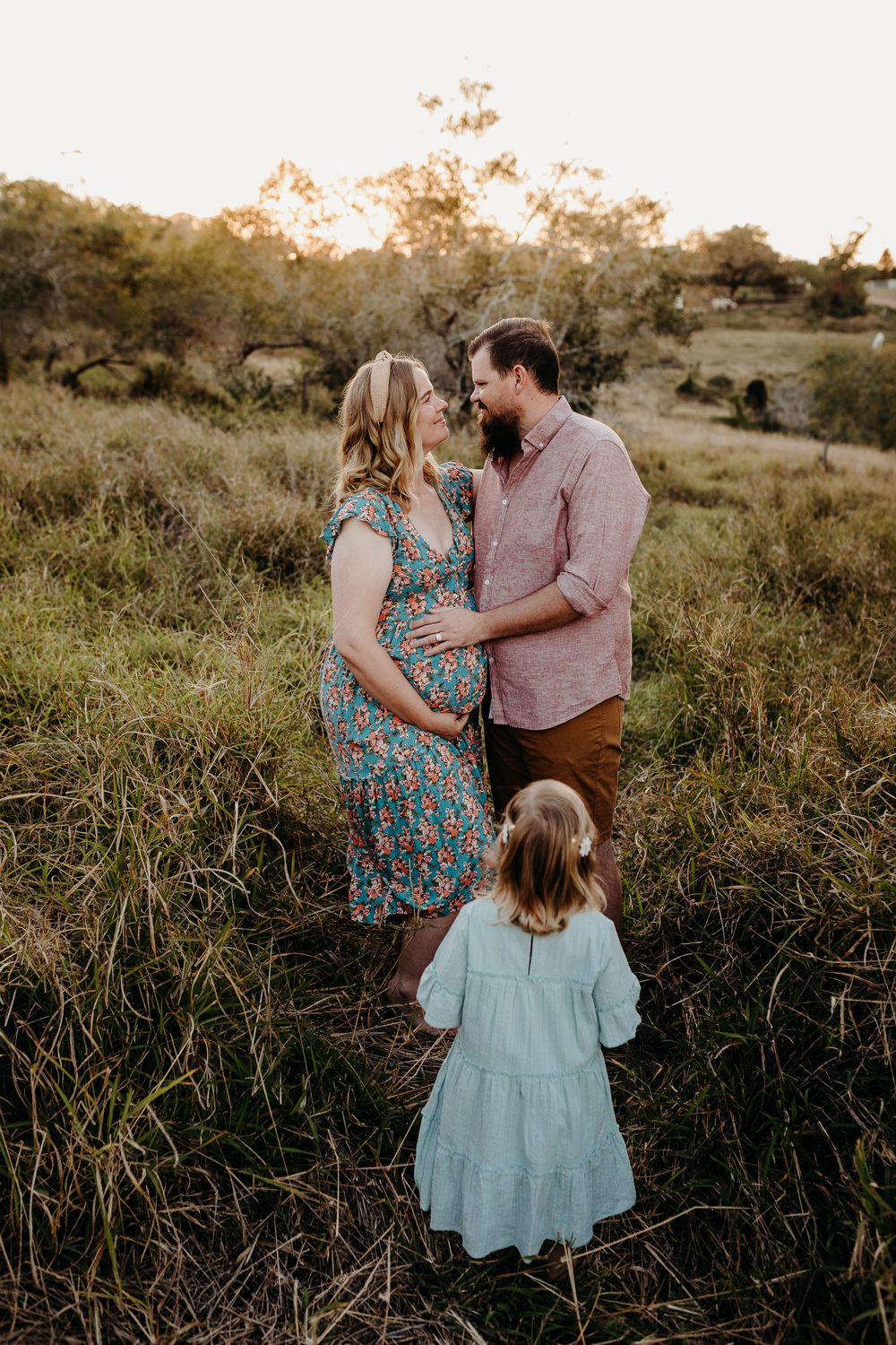 Family portrait session in tall grass during sunset with matching outfits.