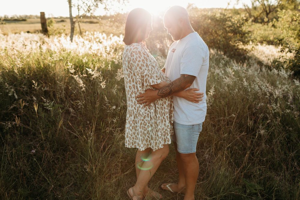 Intimate family moment captured in sunlit field during golden hour.