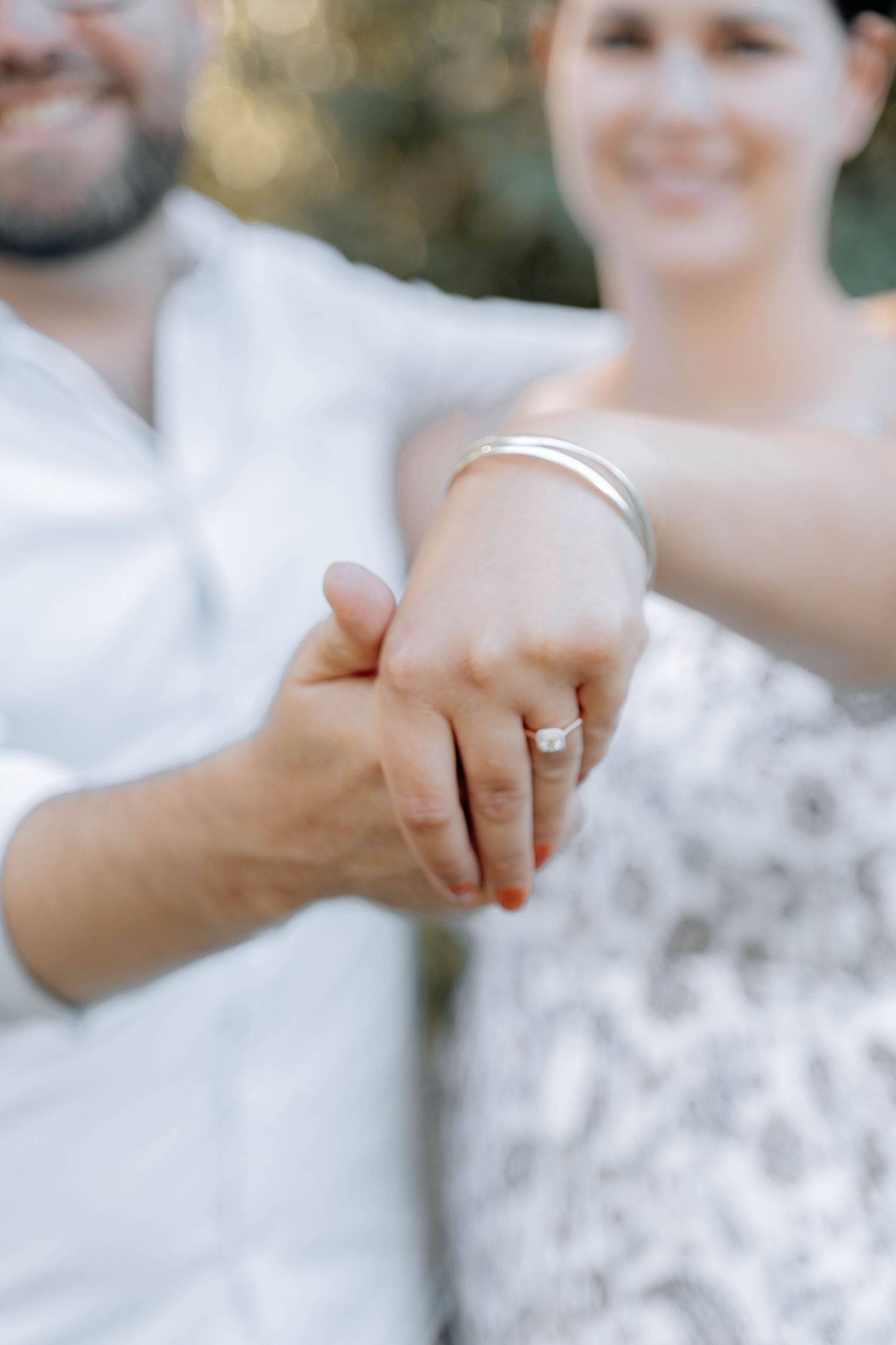 Close-up of hands with wedding rings touching in soft, dreamy lighting.