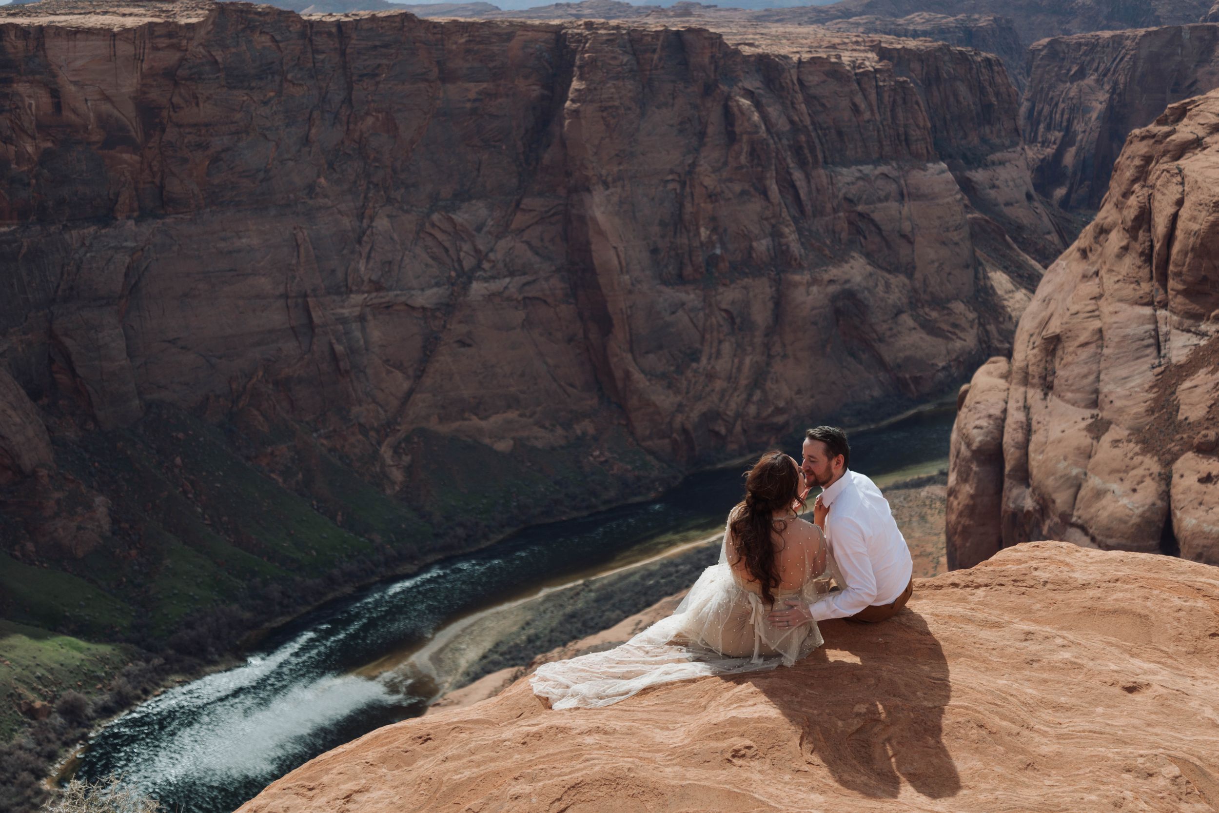 Bride and groom sitting on cliff overlooking Horseshoe Bend