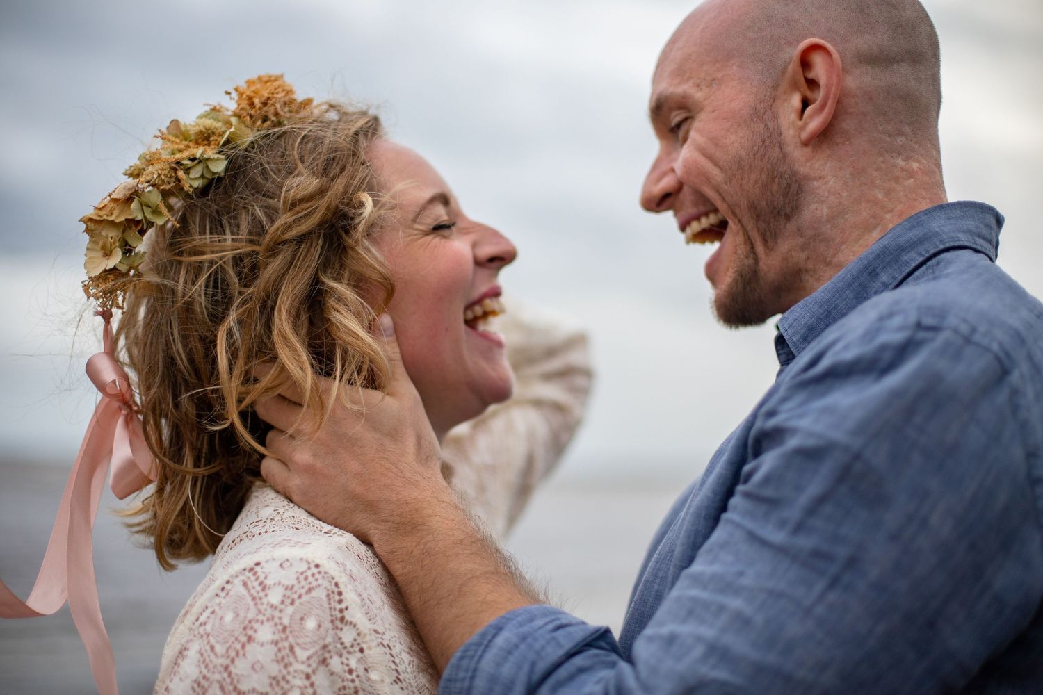Romantic couple sharing a joyful moment outdoors with golden floral crown detail.