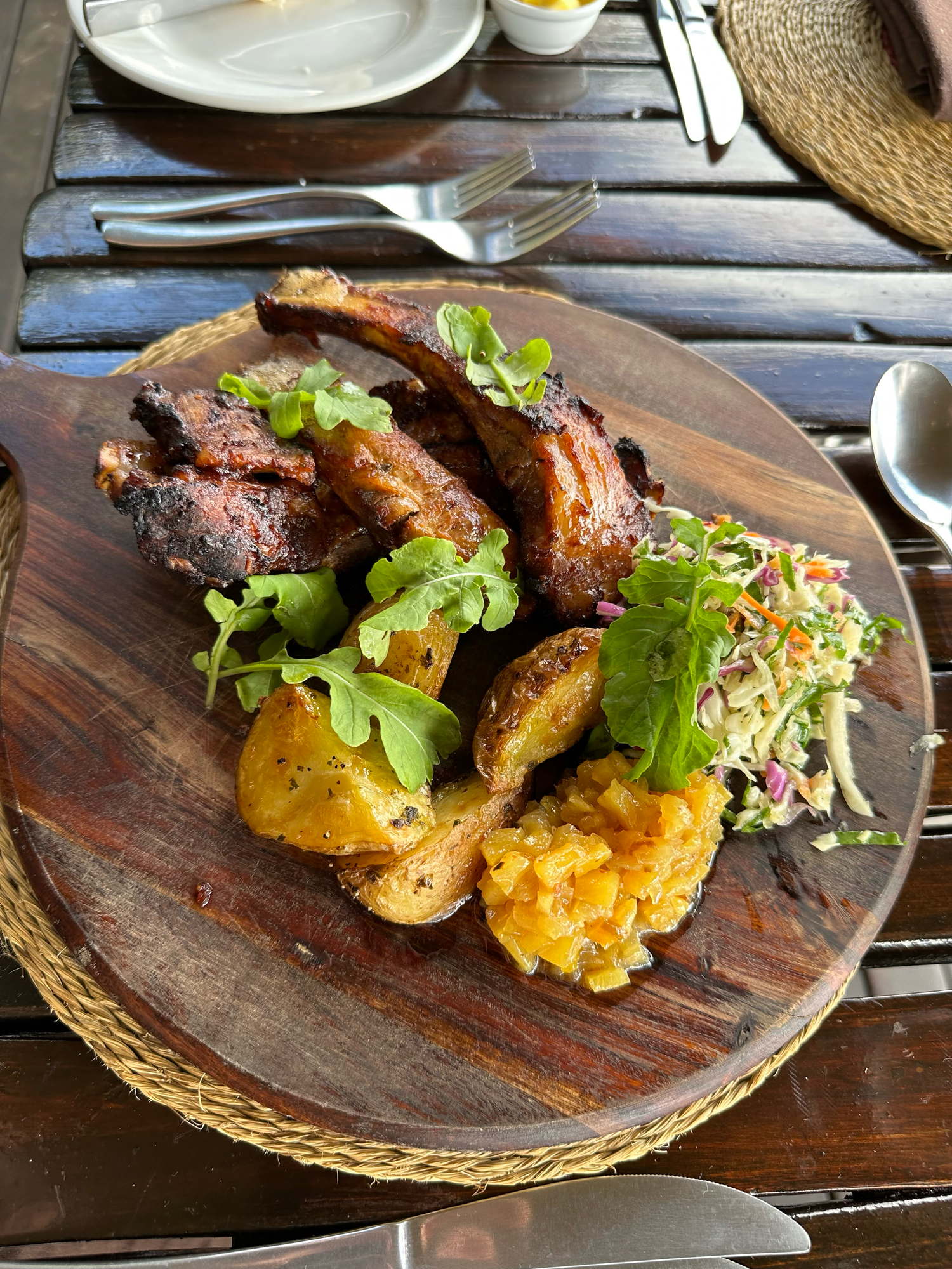 Grilled meat and vegetables served on rustic wooden plates with fresh garnishes.