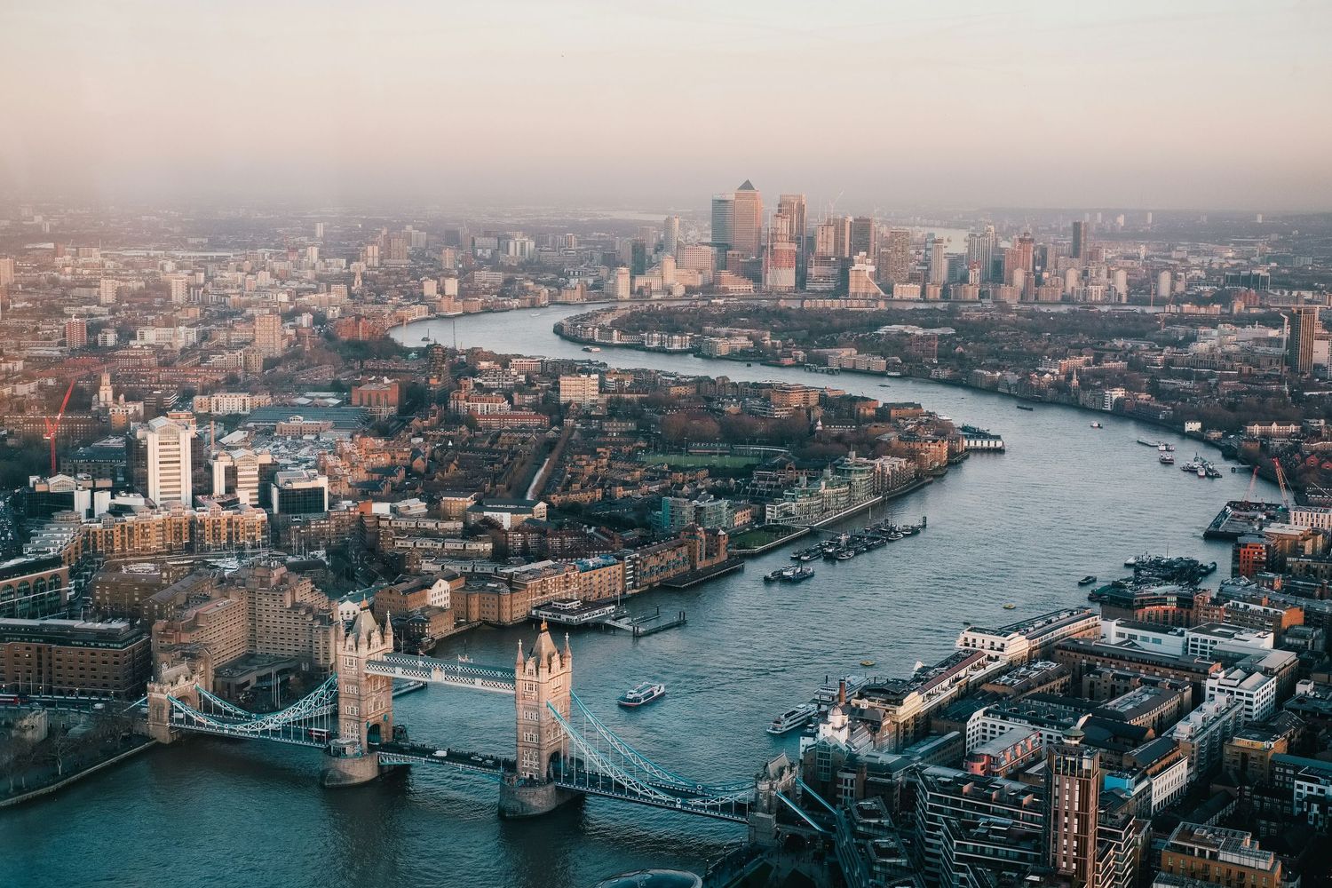 London cityscape at dusk featuring Tower Bridge and Thames River with skyscrapers in background.