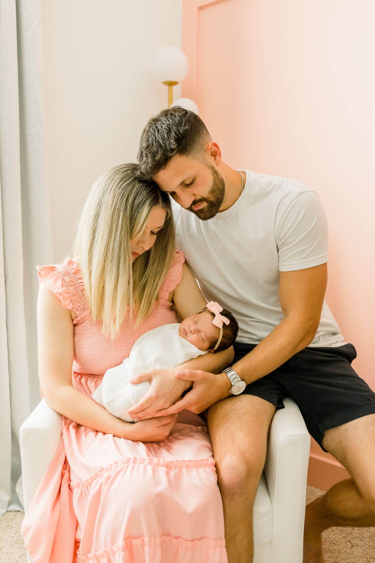 Tender family moment with newborn baby in coral-themed nursery.