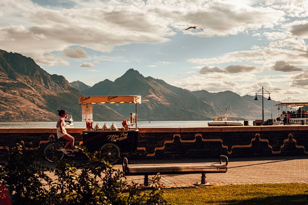 Scenic mountain landscape with an orange gantry crane at a port terminal in golden sunset light.