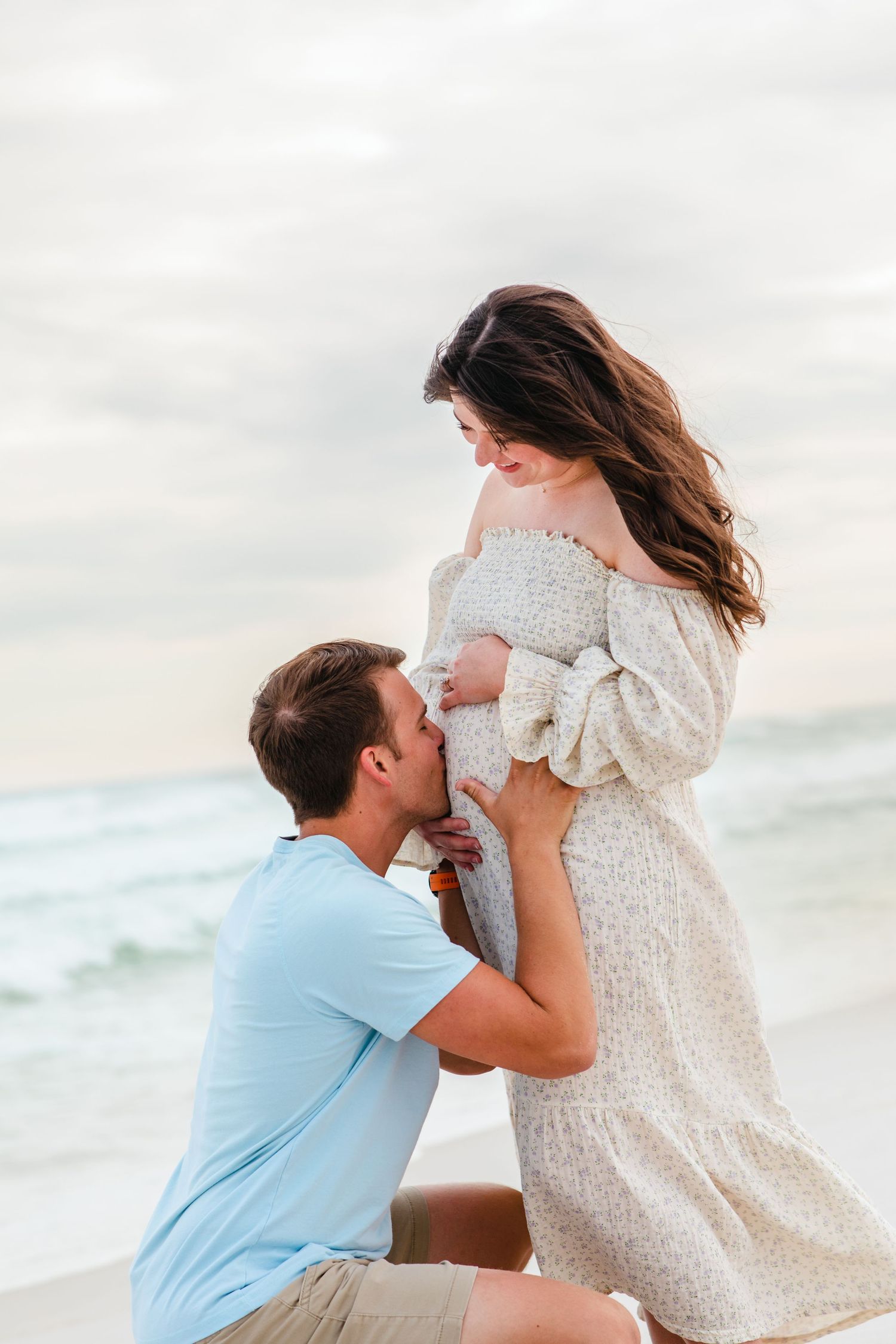 A touching pregnancy announcement scene captured on a beautiful beach at sunset.
