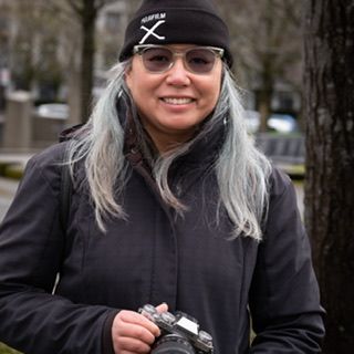Portrait of female photographer smiling outdoors wearing cap, behind the scenes, North Vancouver, Kerrisdale cameras event