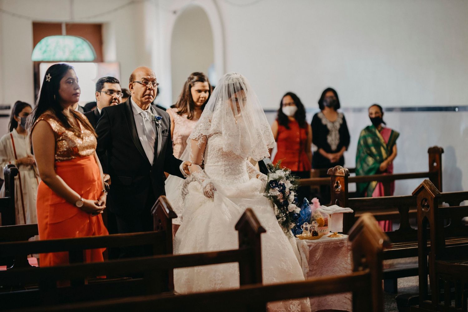 Wedding guests seated in white church pews during an indoor ceremony.