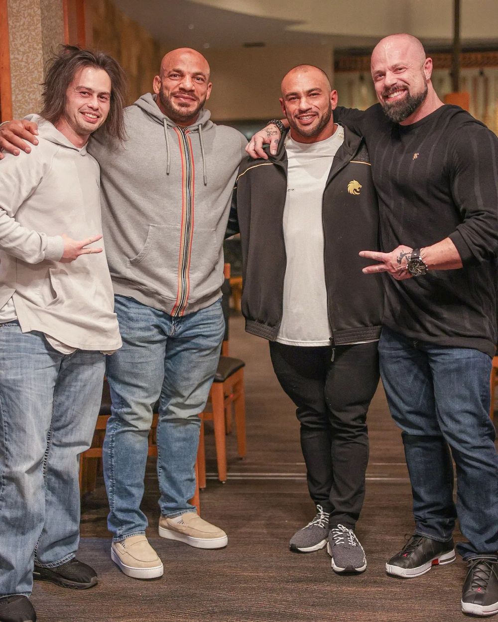 Four friends posing together for casual group photo in restaurant setting.
