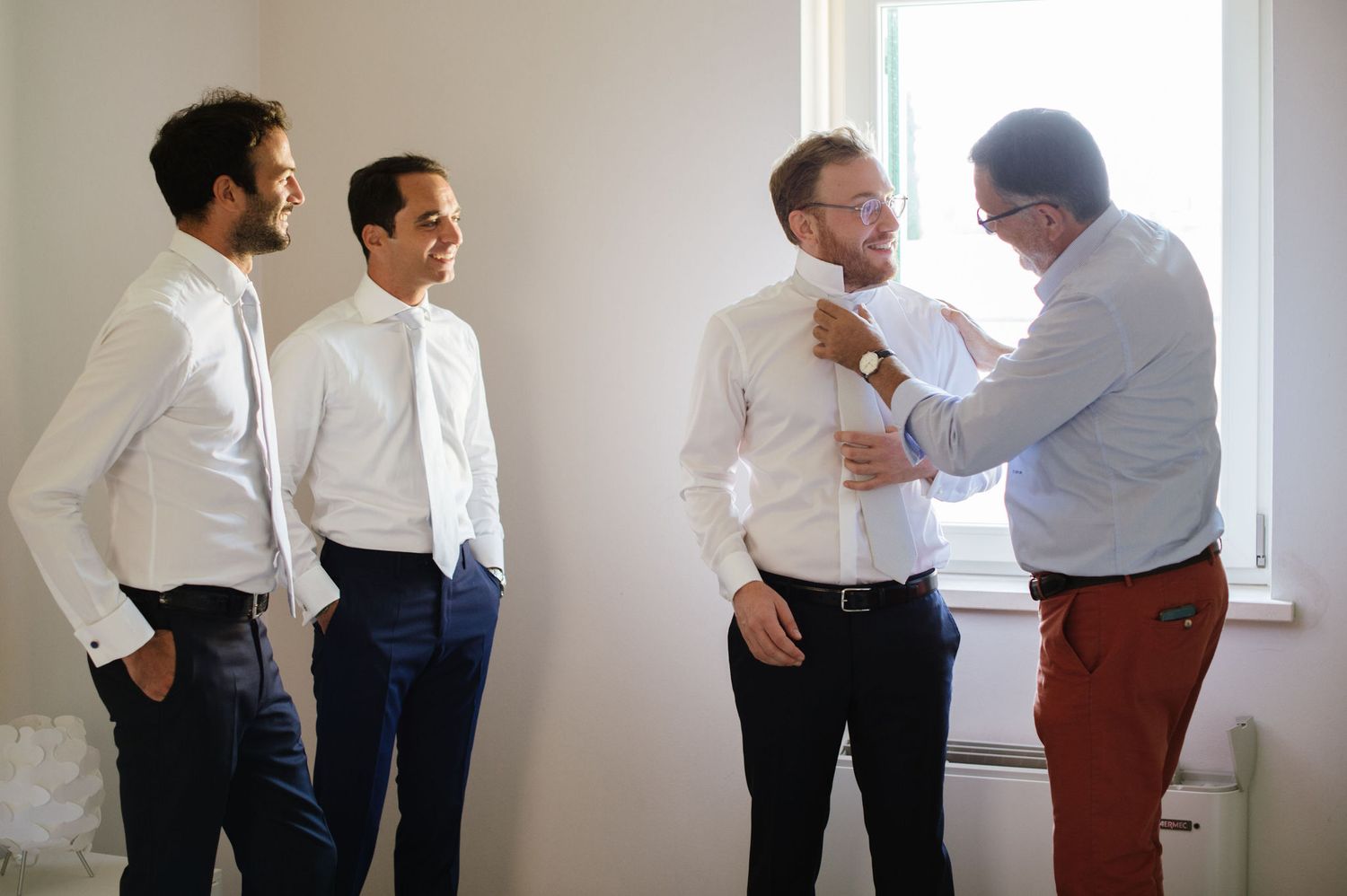 Small group in white shirts and formal attire preparing for an event.