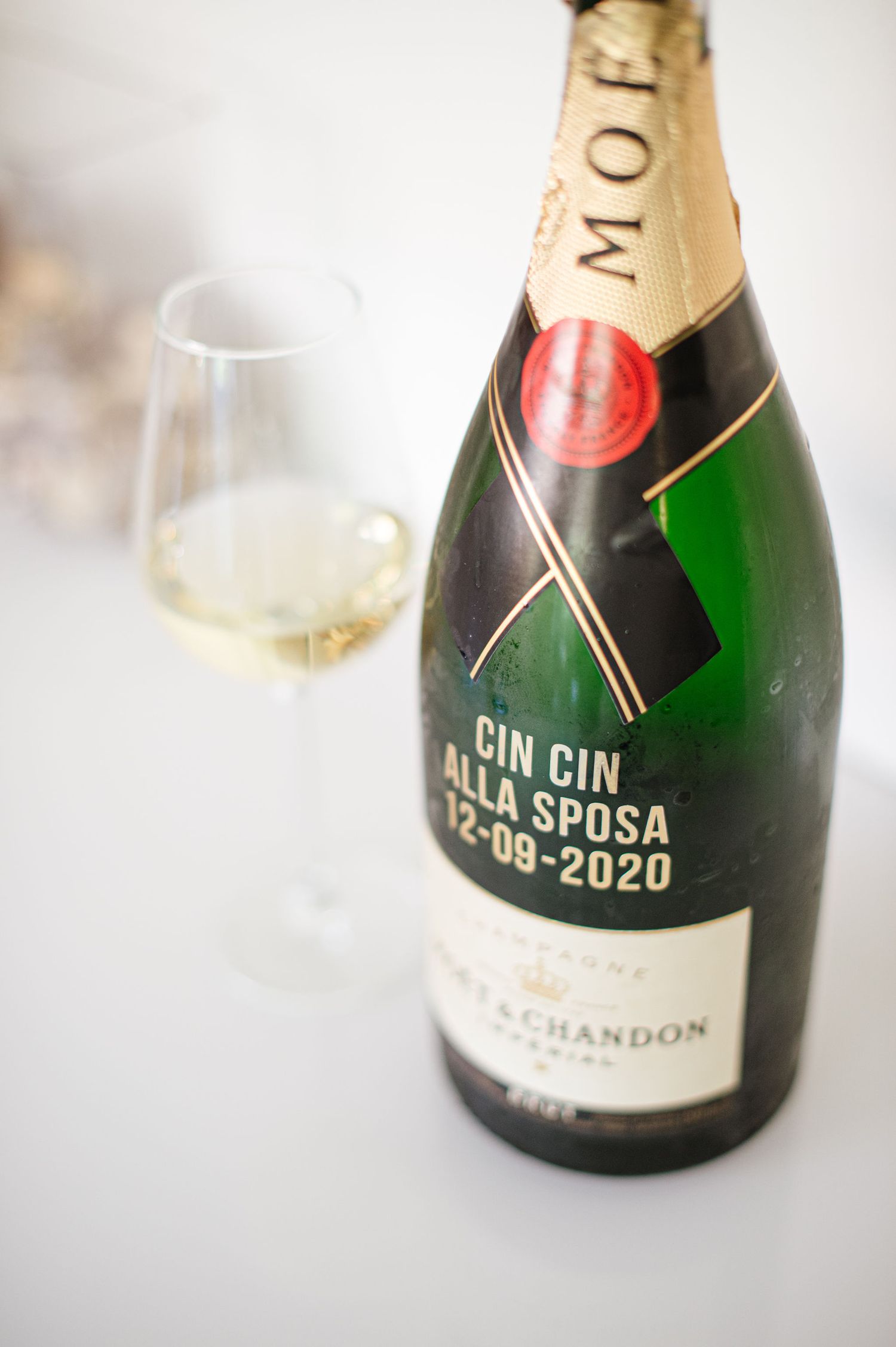 A Moet & Chandon champagne bottle with custom wedding text next to a filled champagne glass.