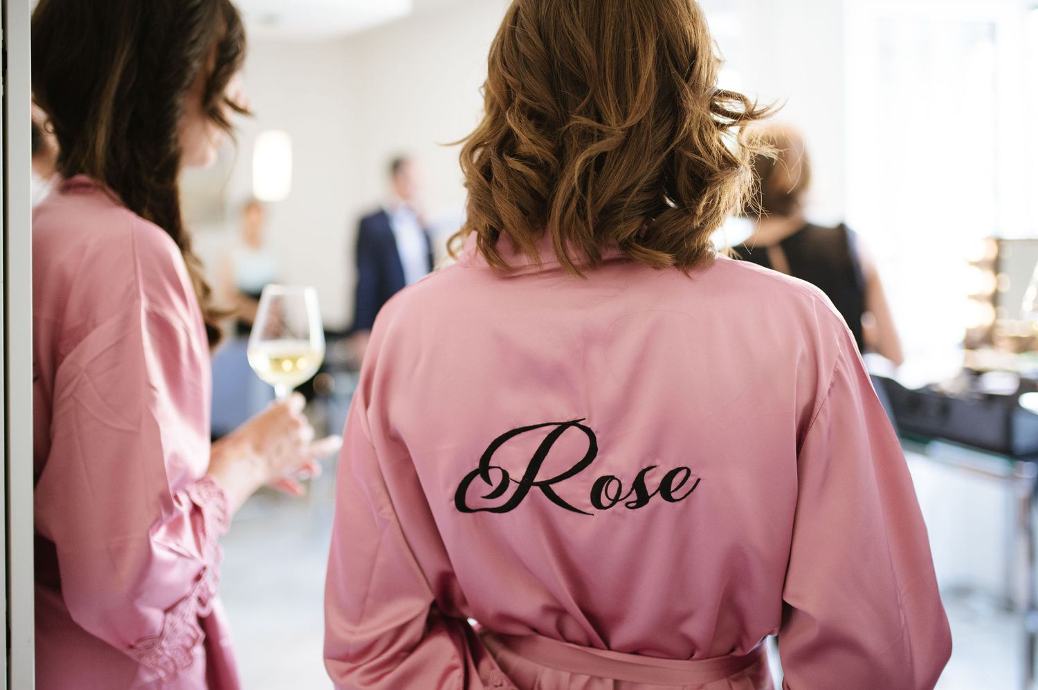 Pink satin robe with 'Rose' embroidered on the back during wedding preparations.