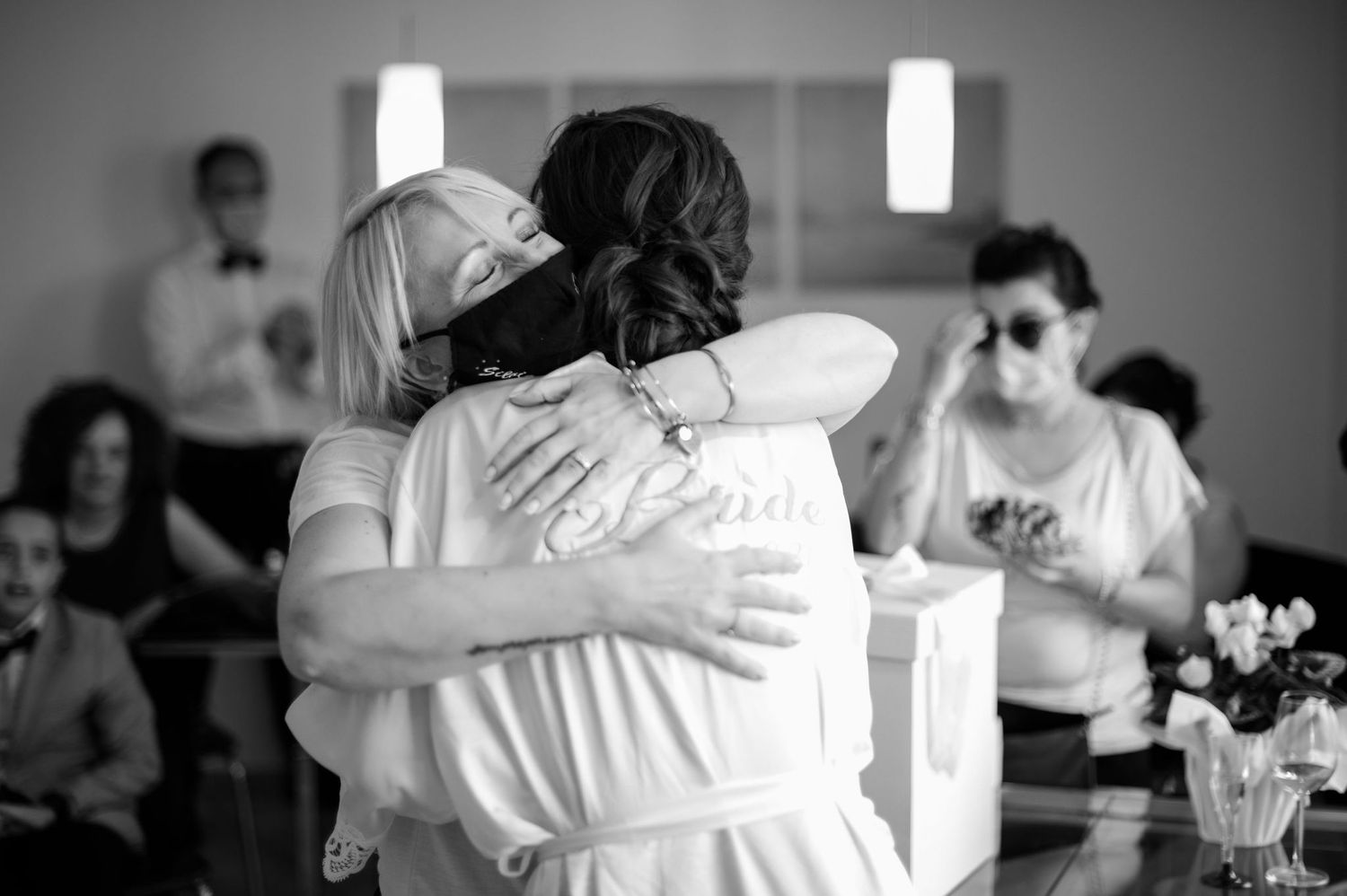 Emotional black and white photo of two people embracing during wedding celebration.