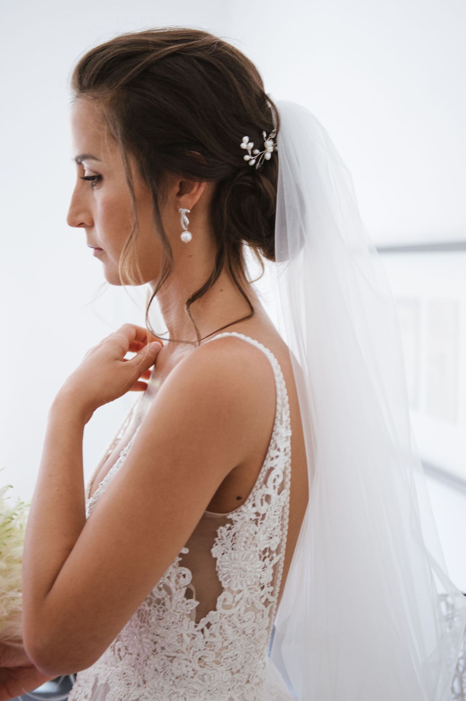 Close-up side profile of a bridal look featuring delicate hair accessories and lace dress details.