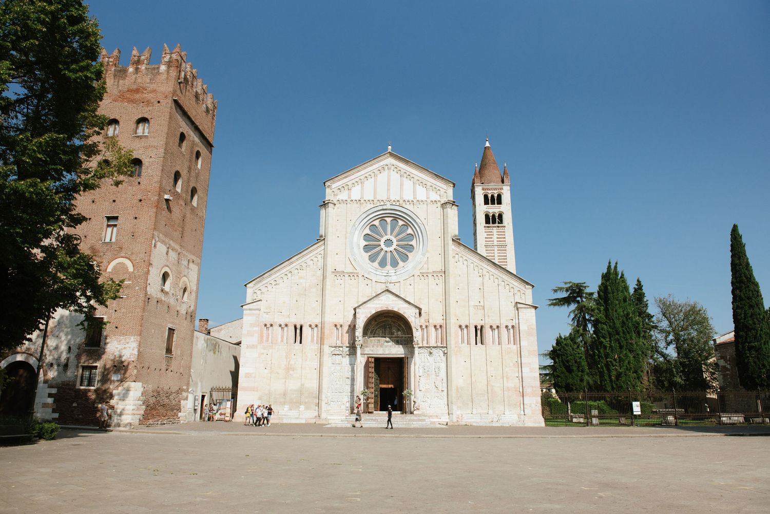 Historic Italian church facade with bell tower and ornate architecture against blue sky.