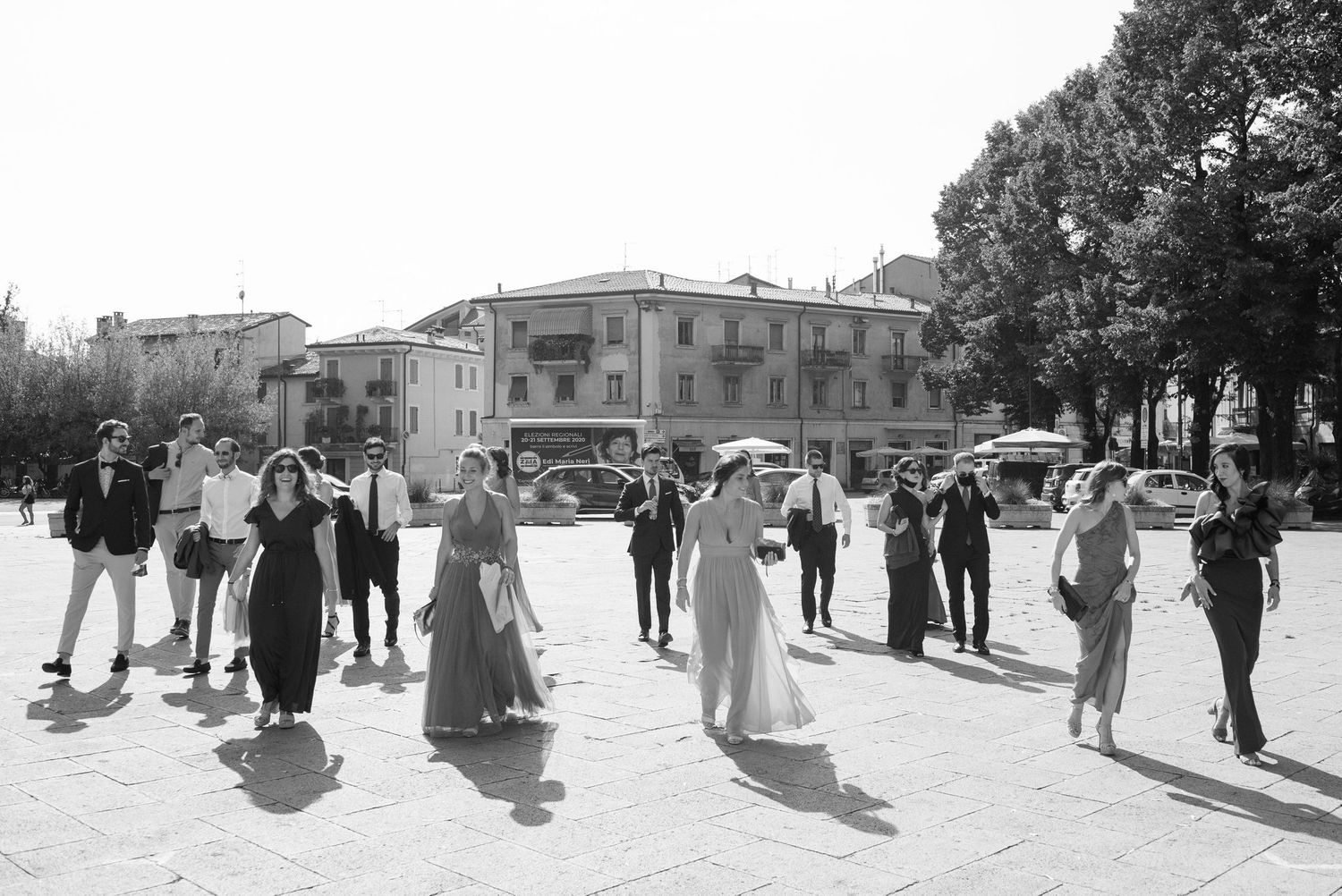 Black and white photo of wedding guests walking in a traditional Italian courtyard.