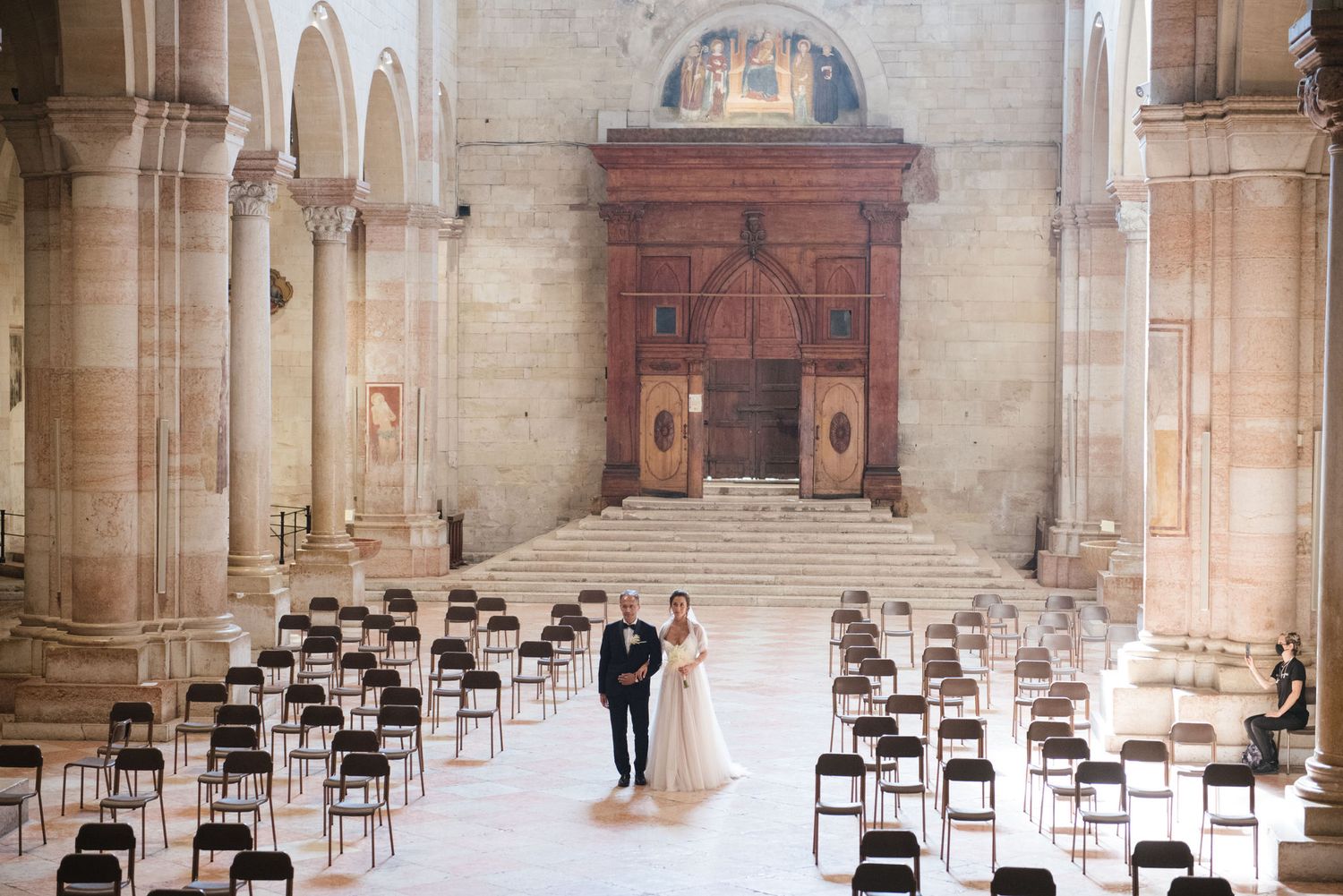A wedding ceremony setup in a historic church with rows of chairs and stone columns.