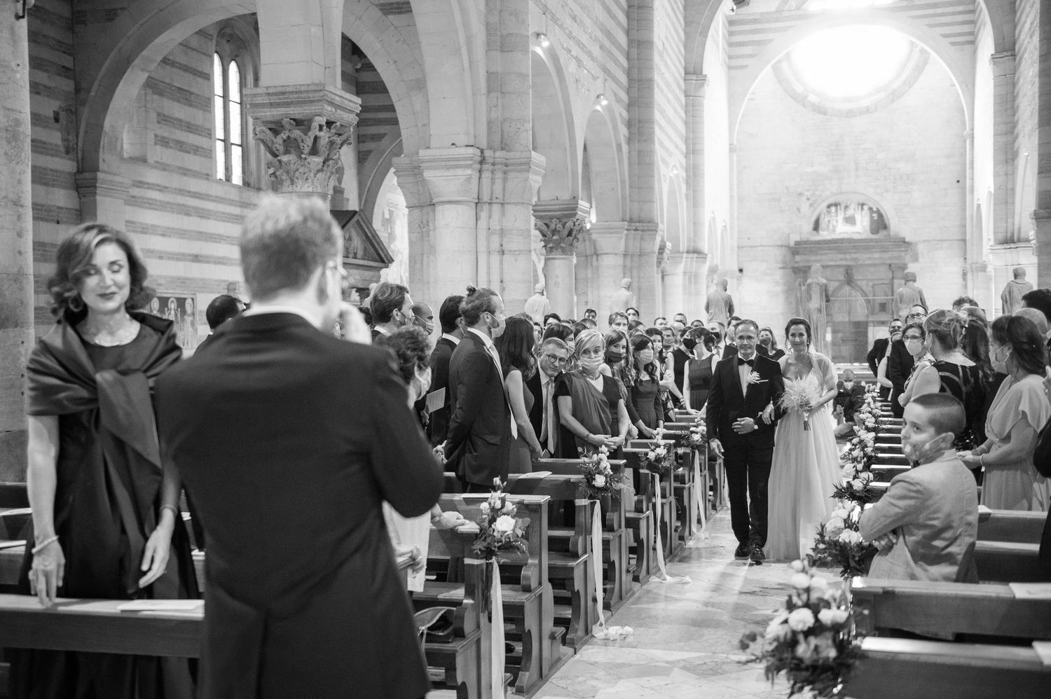 Wedding ceremony taking place inside a historic stone church with striped walls and ornate architecture.