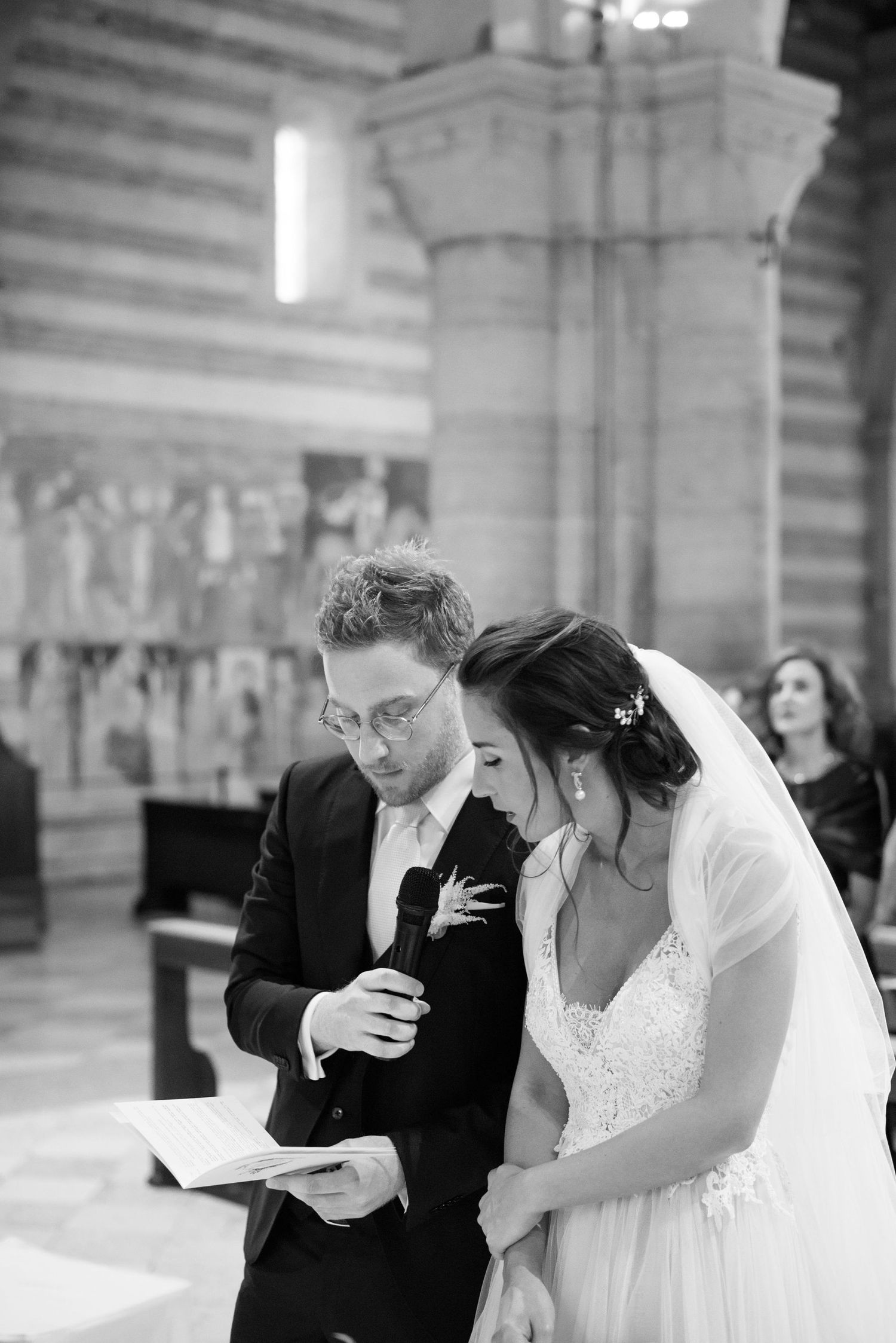 Black and white photo of a couple reading from a document during church wedding ceremony.