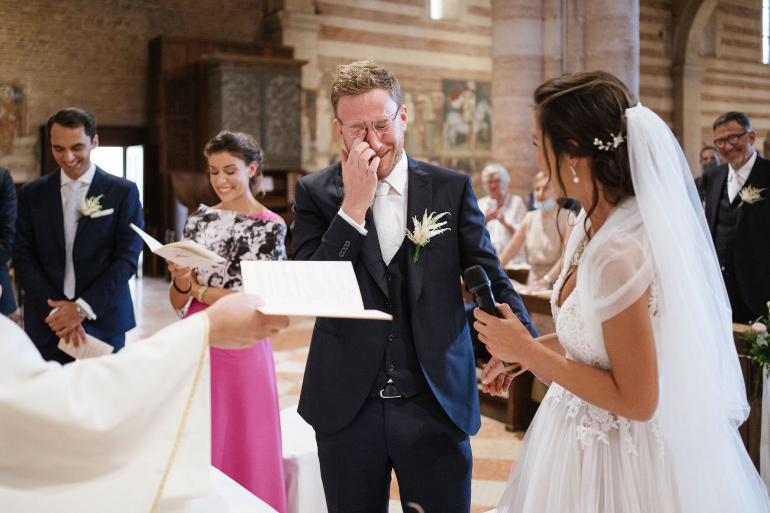 Emotional wedding ceremony moment inside historic Italian church with striped marble walls.